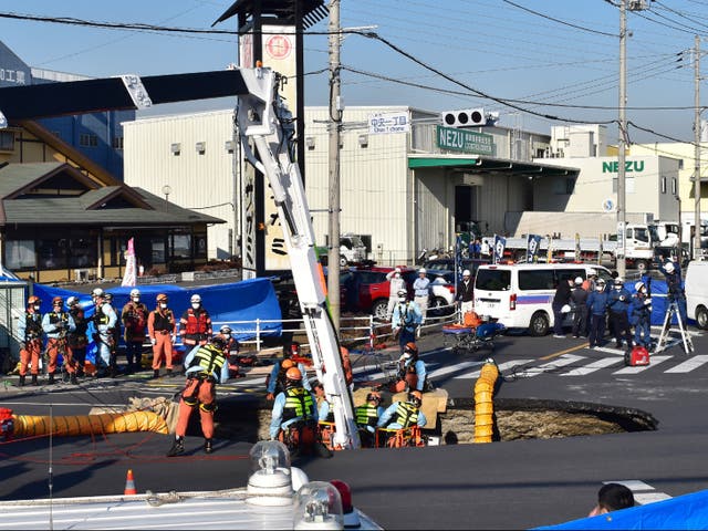 <p>Firefighters work to rescue a truck driver after his vehicle was swallowed up by a sinkhole in the city of Yashio, Japan, on 28 January 2025</p>