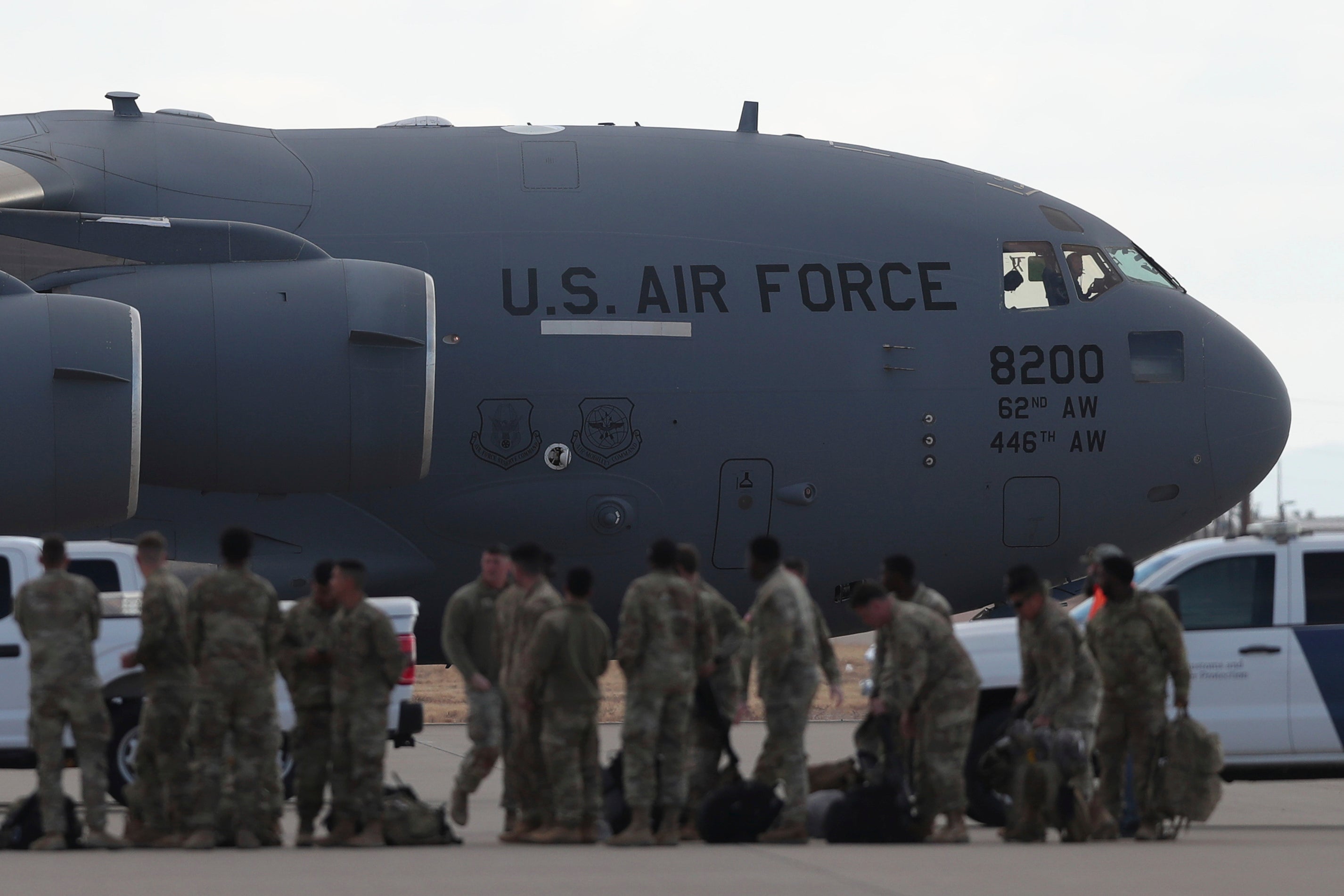 A U.S. military aircraft carrying migrants to be deported to Guatemala is ready for takeoff as soldiers stand on the tarmac at Fort Bliss in El Paso