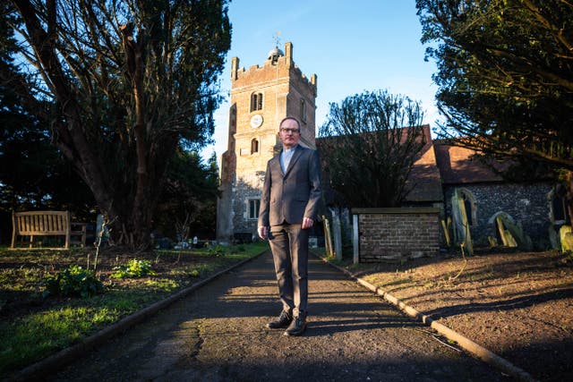 The Revd Richard Young poses outside St Mary the Virgin Church, where he works as a priest, in the village of Harmondsworth, west London (James Manning/PA)