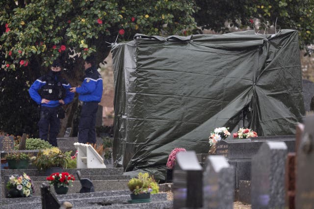 <p>French gendarmes stand guard as a tarpaulin covers the vandalised tombstone of the late far-right leader Jean-Marie Le Pen</p>