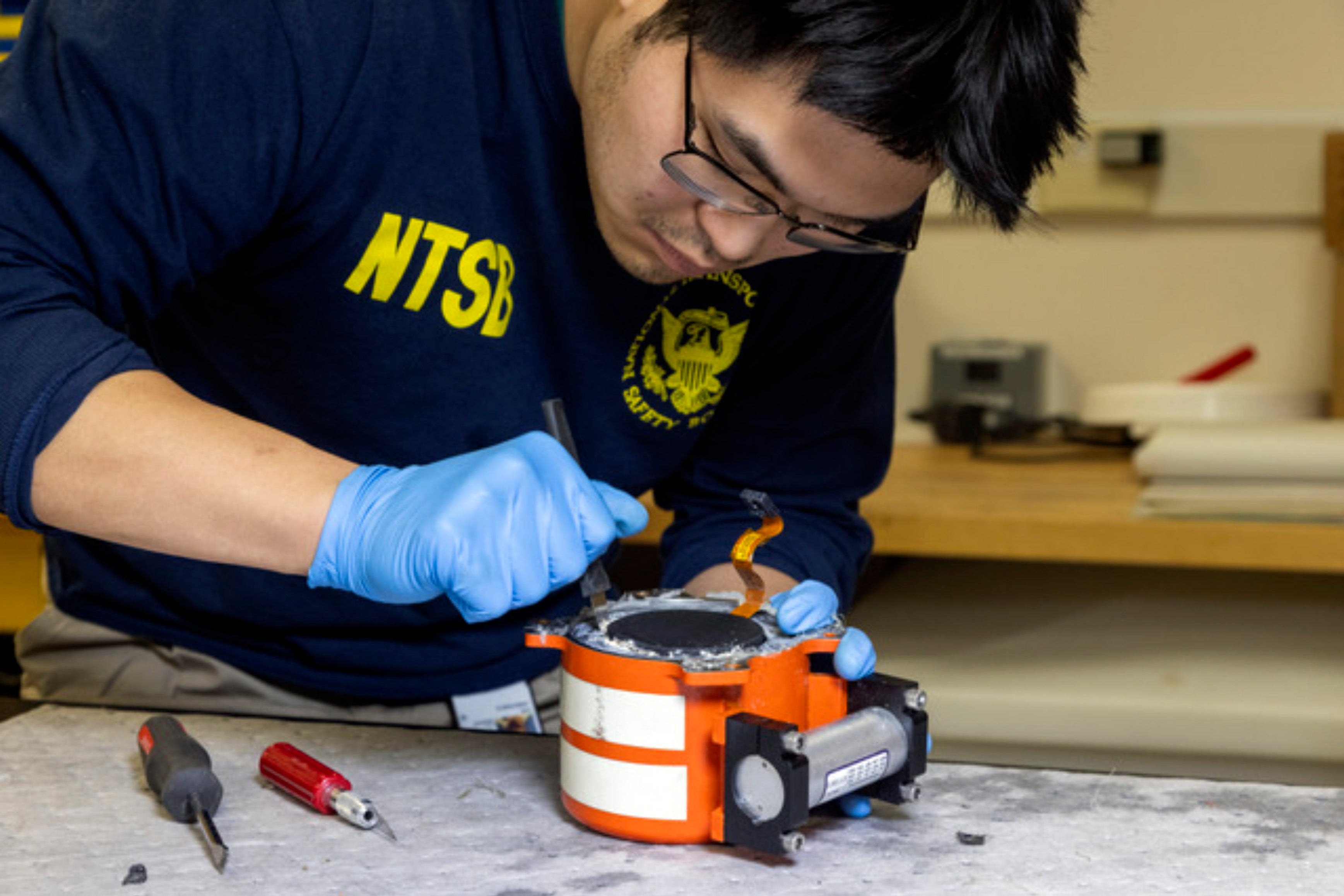 In this image provided by the National Transportation Safety Board, an NTSB investigator examines cockpit voice recorder and flight data recovered from the American Airlines passenger jet that crashed with an Army helicopter Wednesday night near Ronald Reagan Washington National Airport