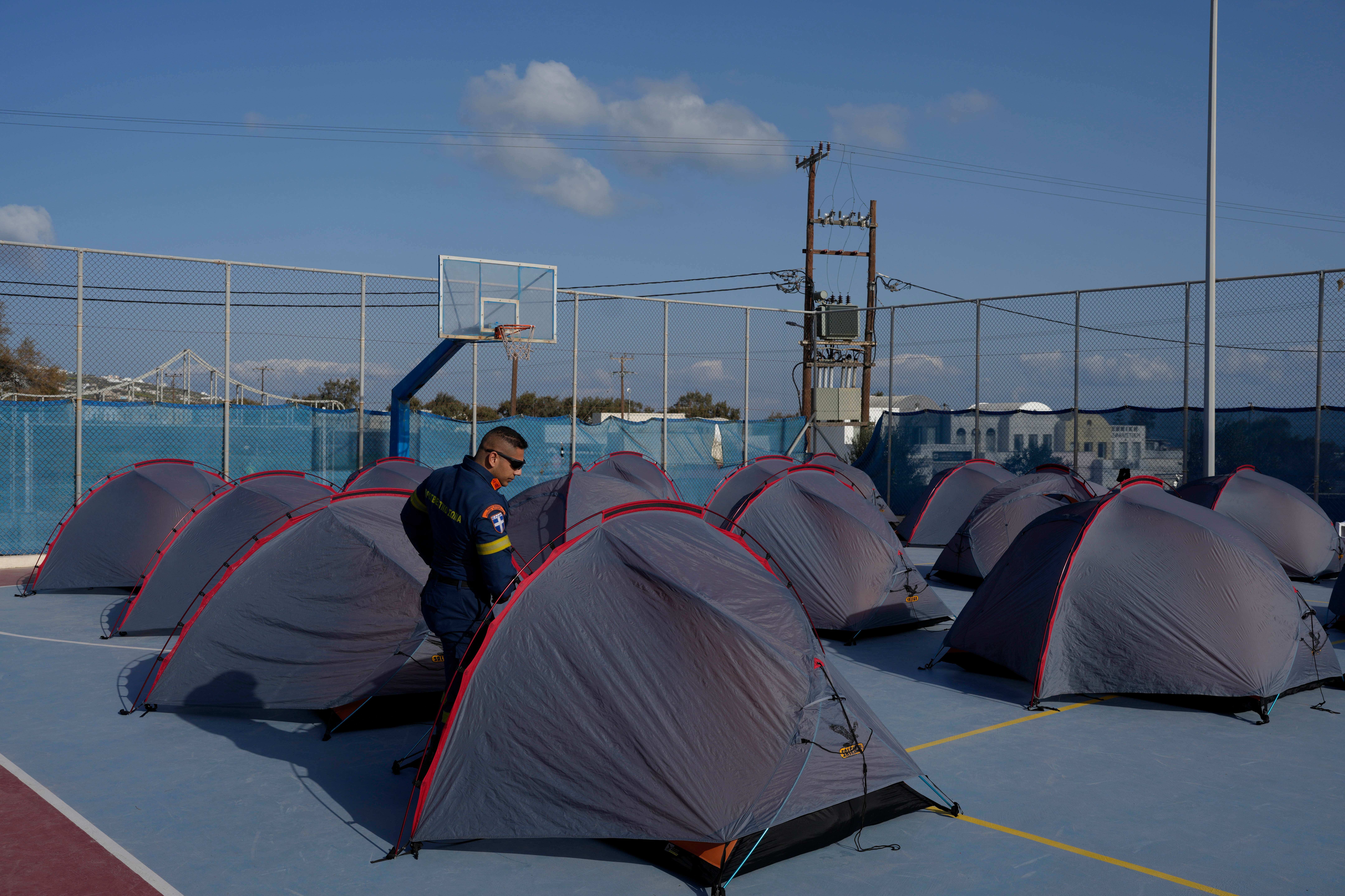 A firefighter walks among tents set up at a basketball court to accommodate Fire Service rescuers as Greek authorities are taking emergency measures in response to intense seismic activity on the popular Aegean Sea holiday island of Santorini, southern Greece, Monday, Feb. 3