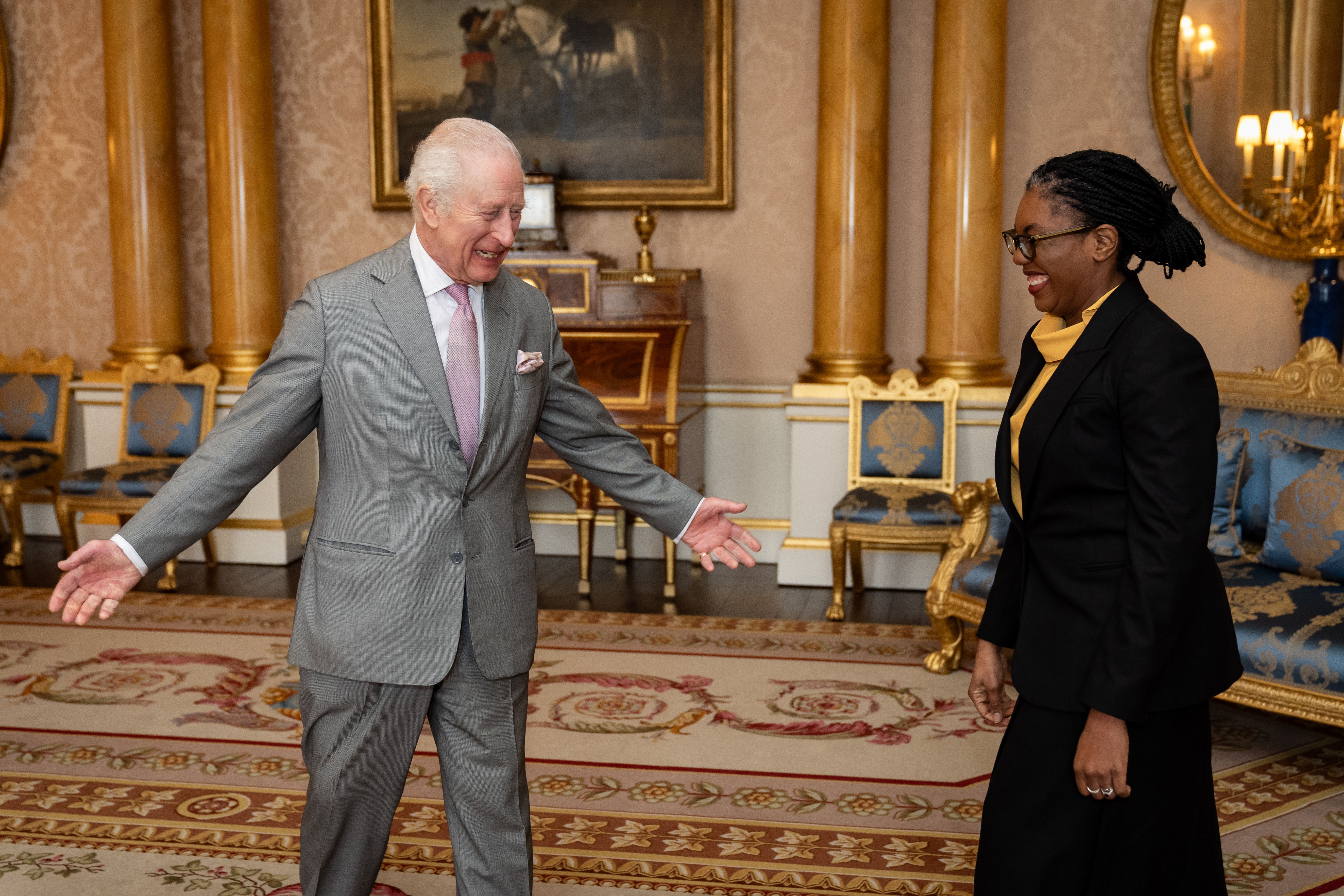 The King holds his arms wide as he greets a smiling Kemi Badenoch (Aaron Chown/PA)