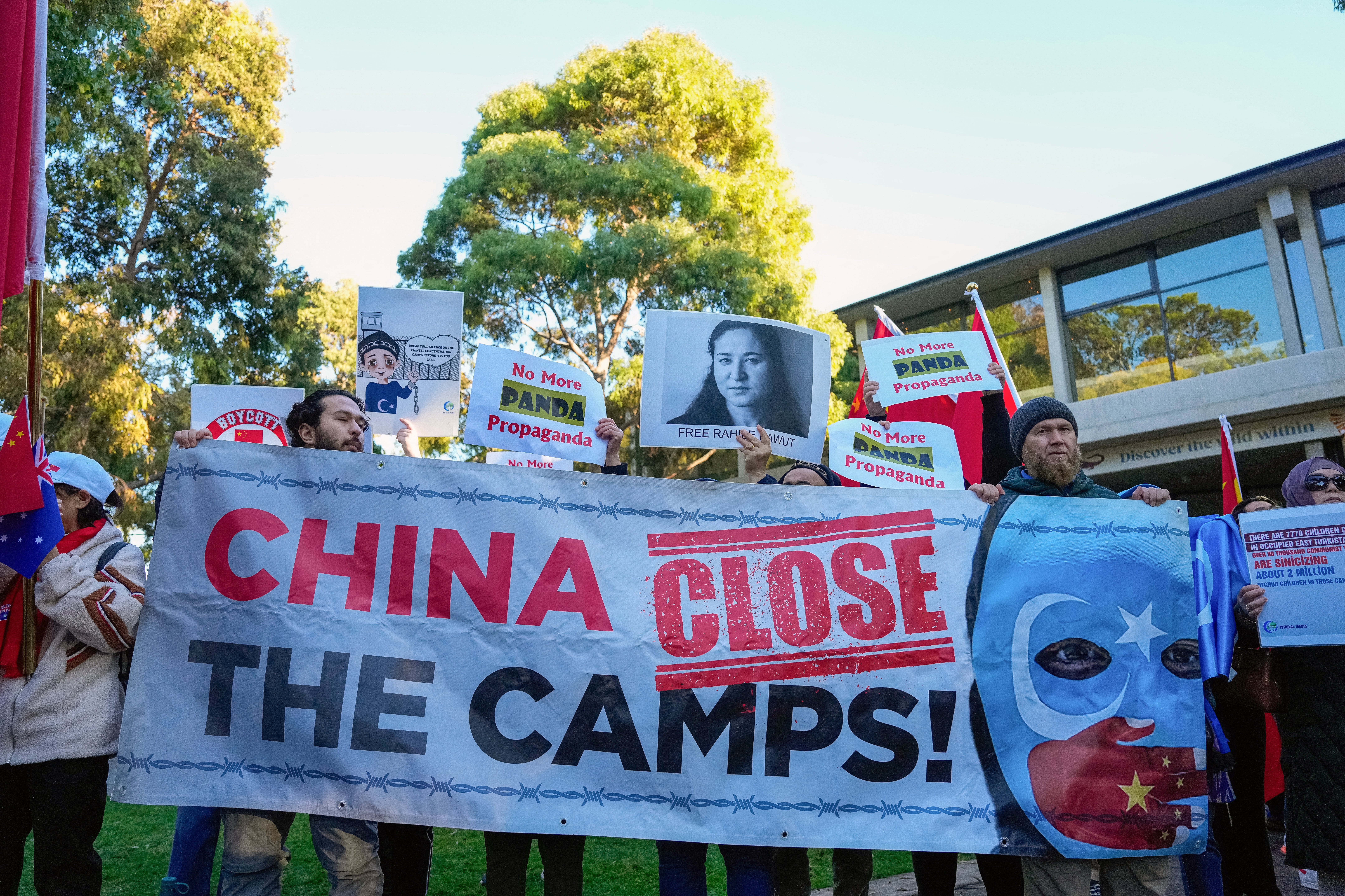 File. Uyghur protesters hold placards and a banner as they await the arrival of Chinese premier Li Qiang at the Adelaide Zoo in Australia on 16 June 2024