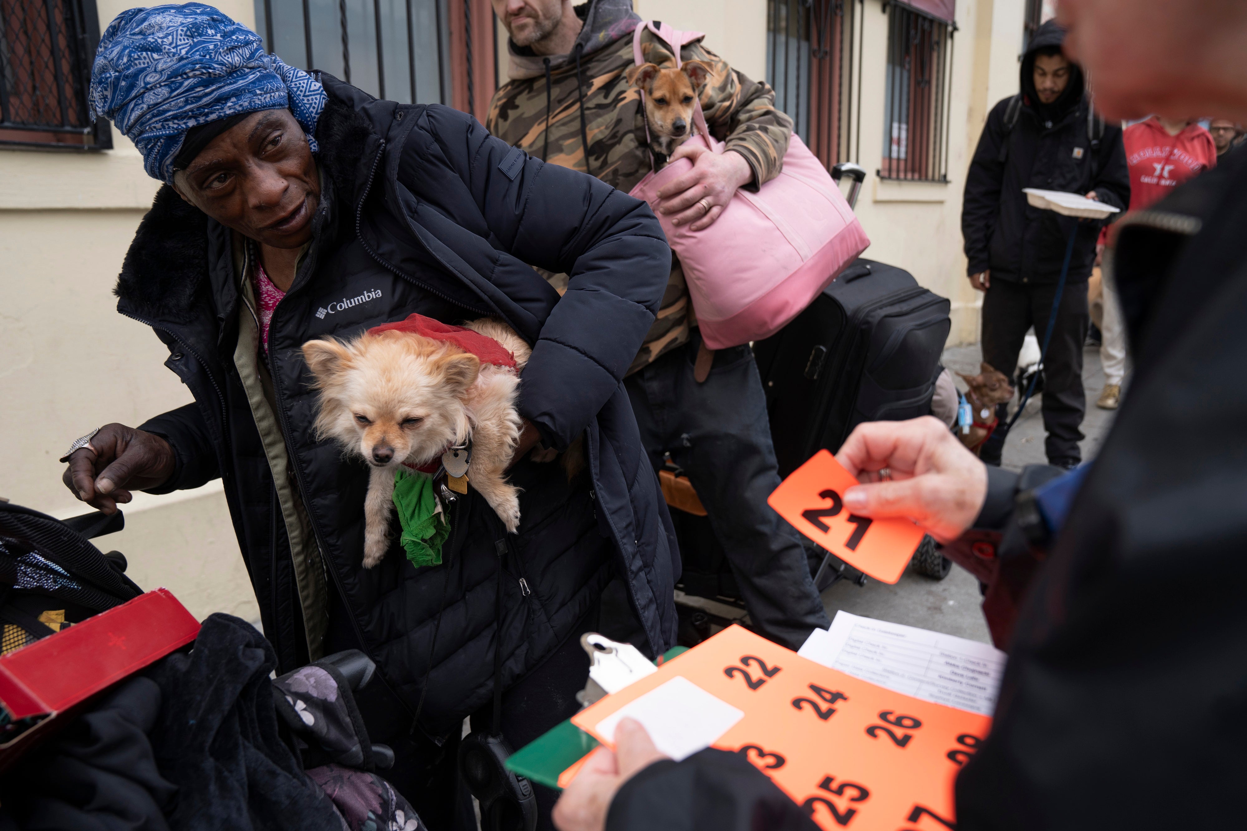 Evelyn Johnson and her dog Baby Girl, 5, receive a number from a volunteer as they wait in line at a free dog vaccine clinic to combat a canine Parvovirus outbreak