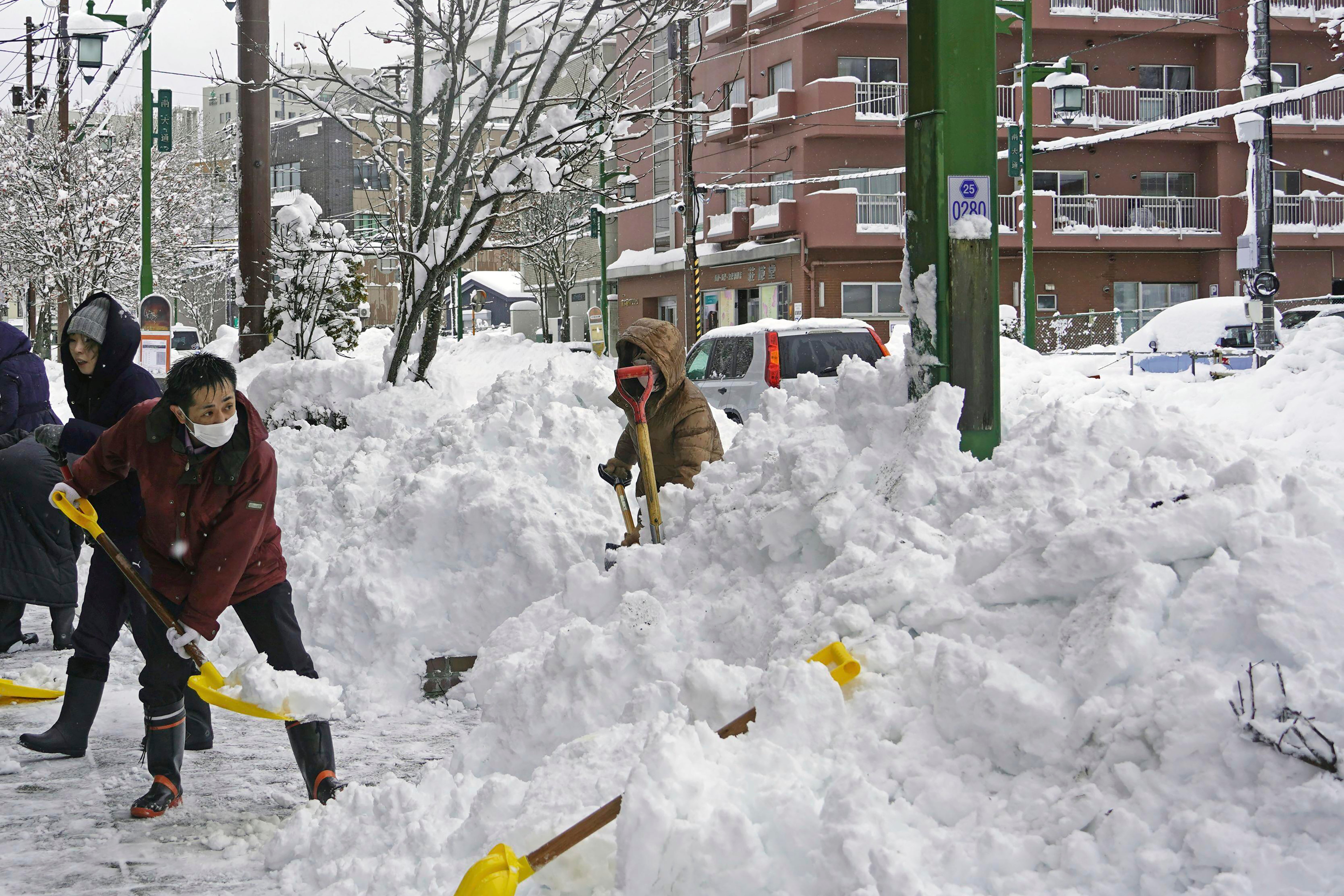 People remove snow from a street in Kushiro, Hokkaido