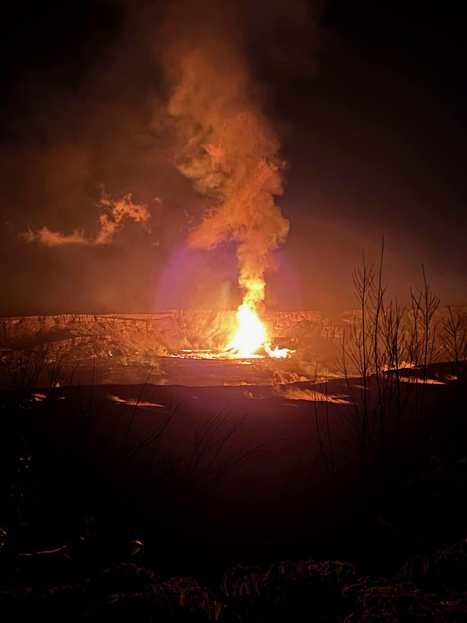 A lava fountain erupting and gushing molten lava onto a crater floor taken from Kūpinaʻi Pali in Hawaii