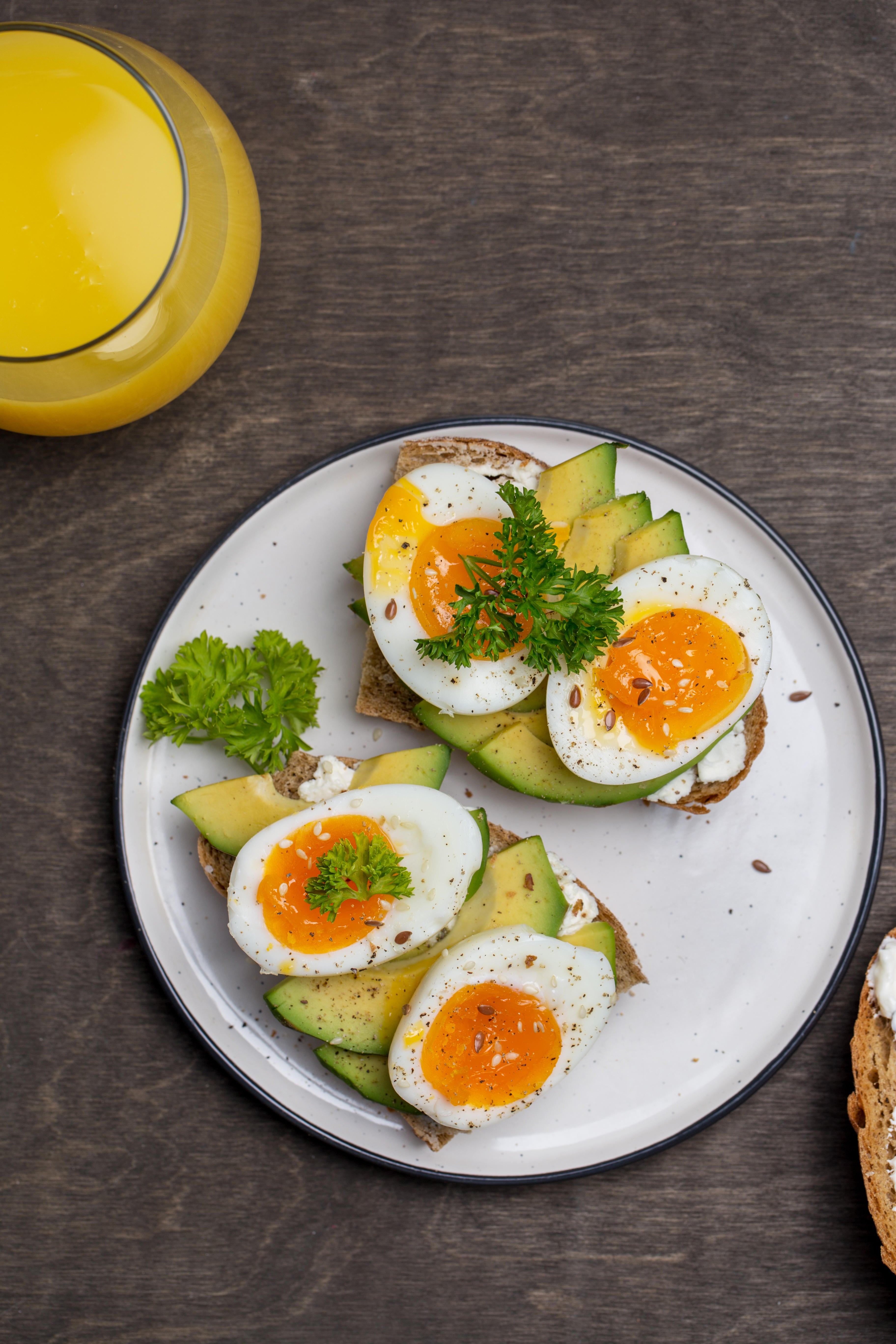 Avocado and boiled eggs on grain bread on a white plate next to a glass of orange juice (Alamy/PA)