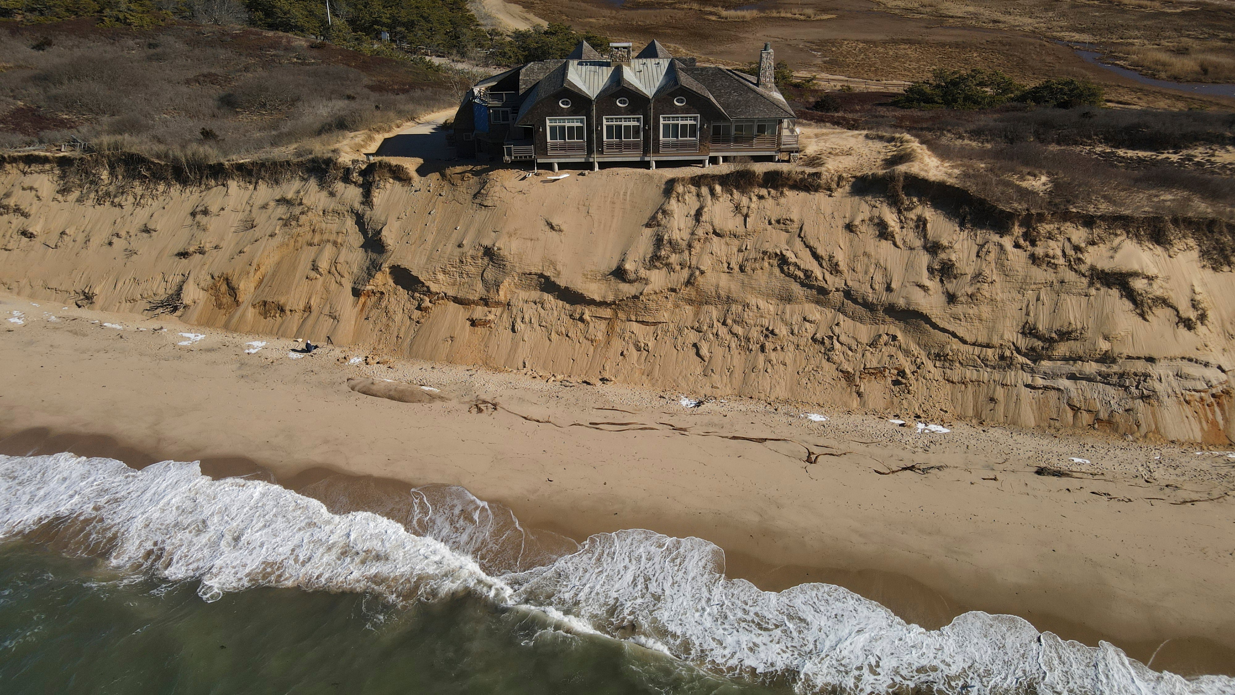 A home sits atop of a sandy bluff overlooking a beach in Wellfleet