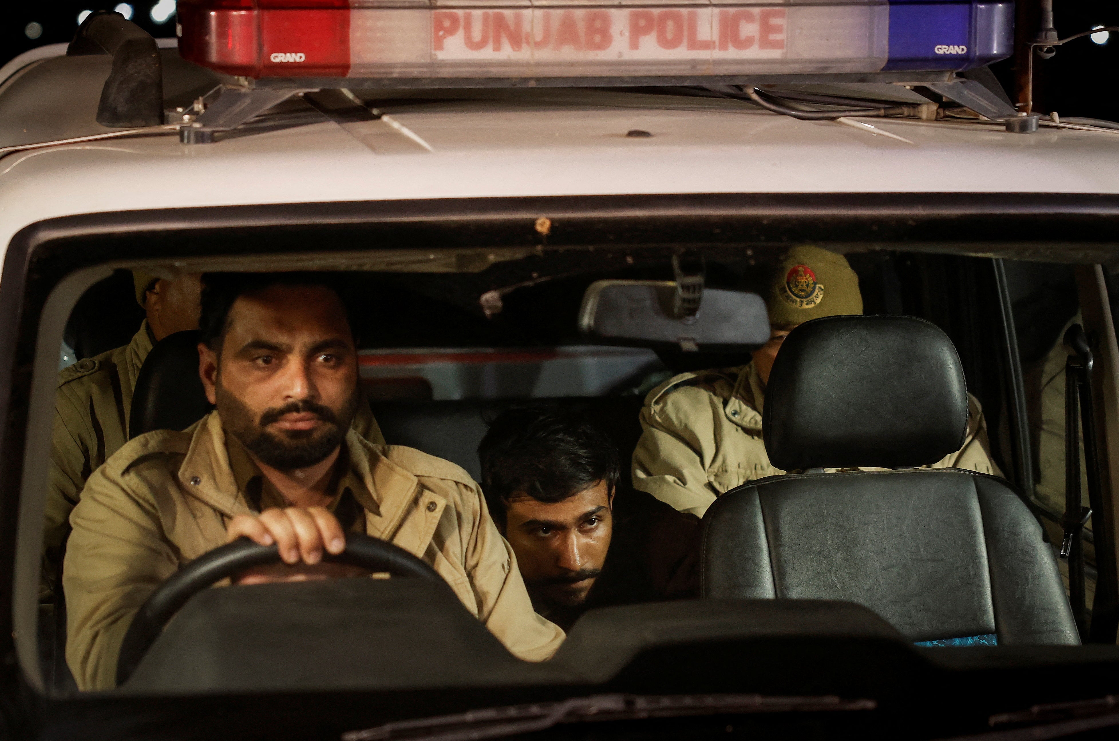 An Indian immigrant deported from the US sits in a police vehicle as they leave the airport in Amritsar, India on 5 February