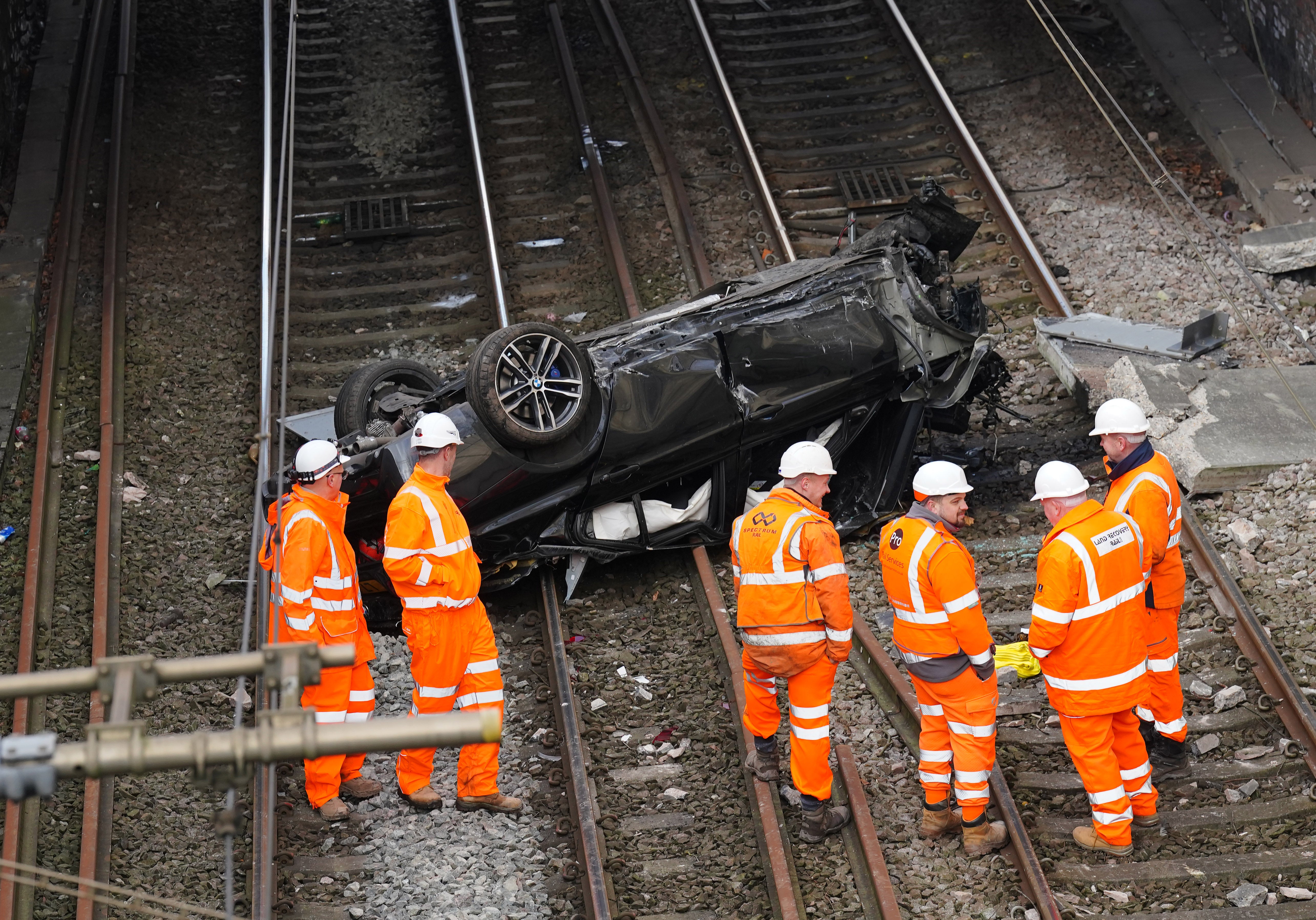 Emergency workers view a car that crashed onto tracks in the early hours on Friday morning