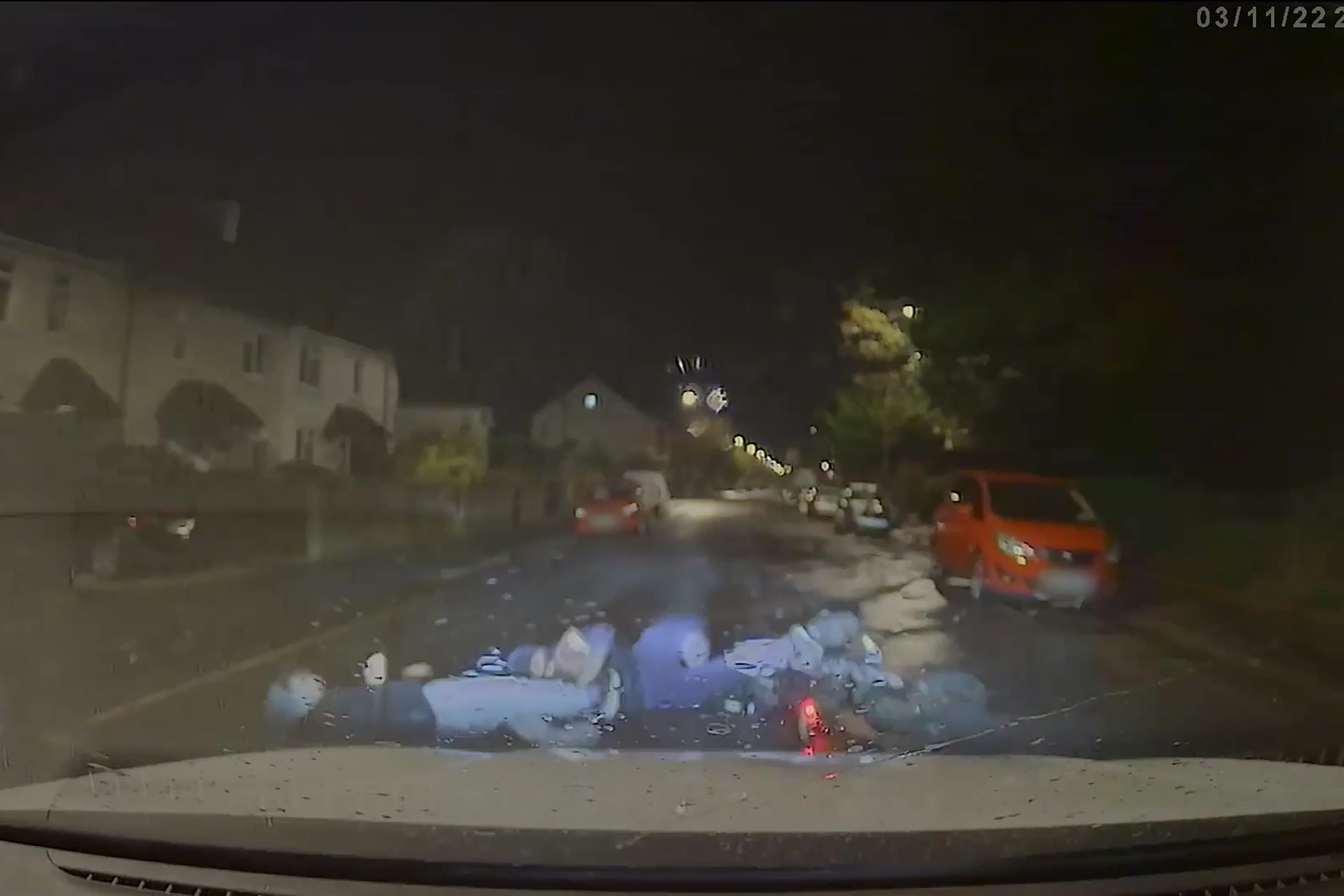 A video screen grab shows the moment a marked police car knocks the rider and pillion passenger off an electric motorbike (Court handout/PA)