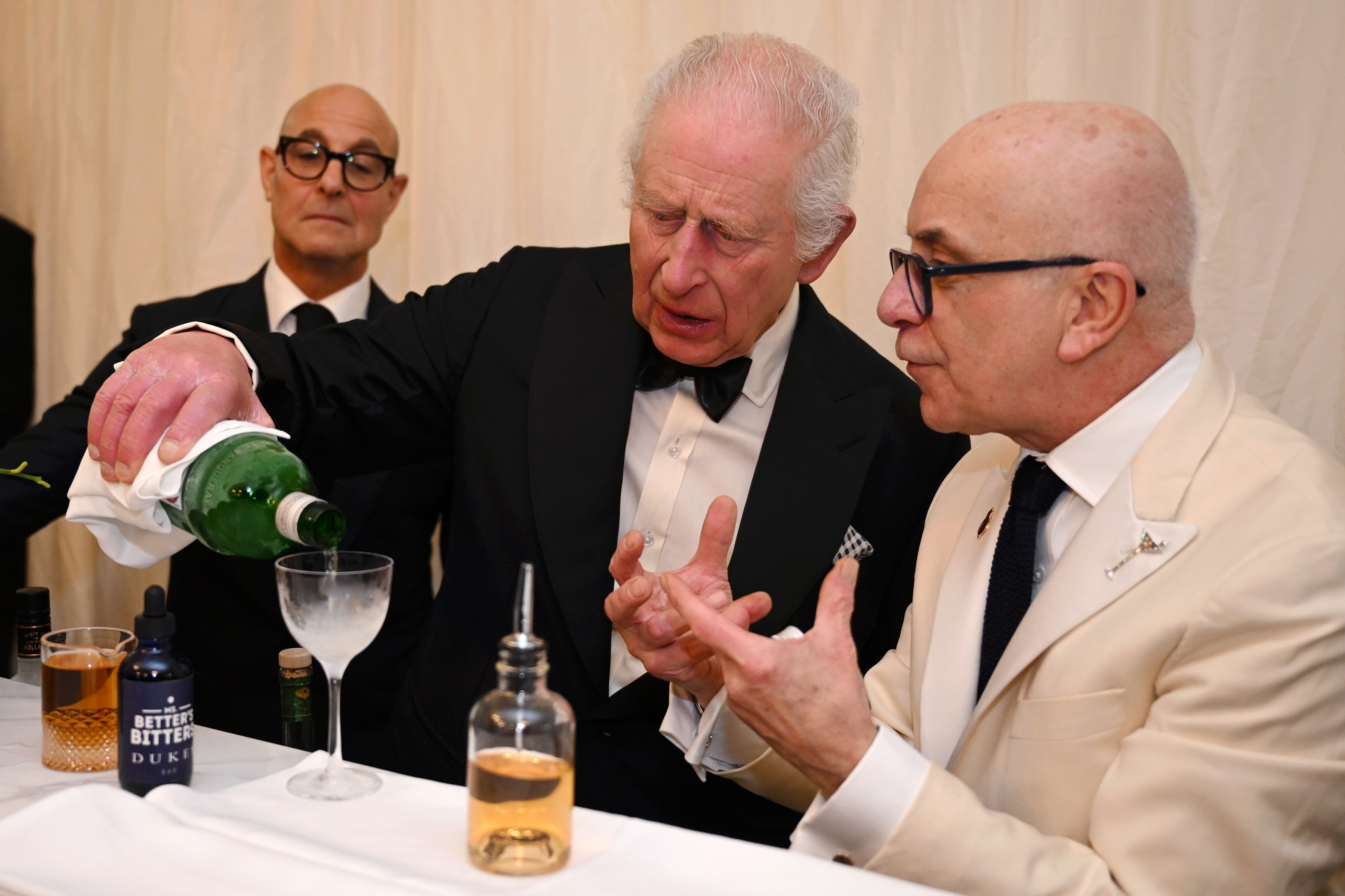 King Charles pours a martini, with Stanley Tucci (left) watching over his shoulder