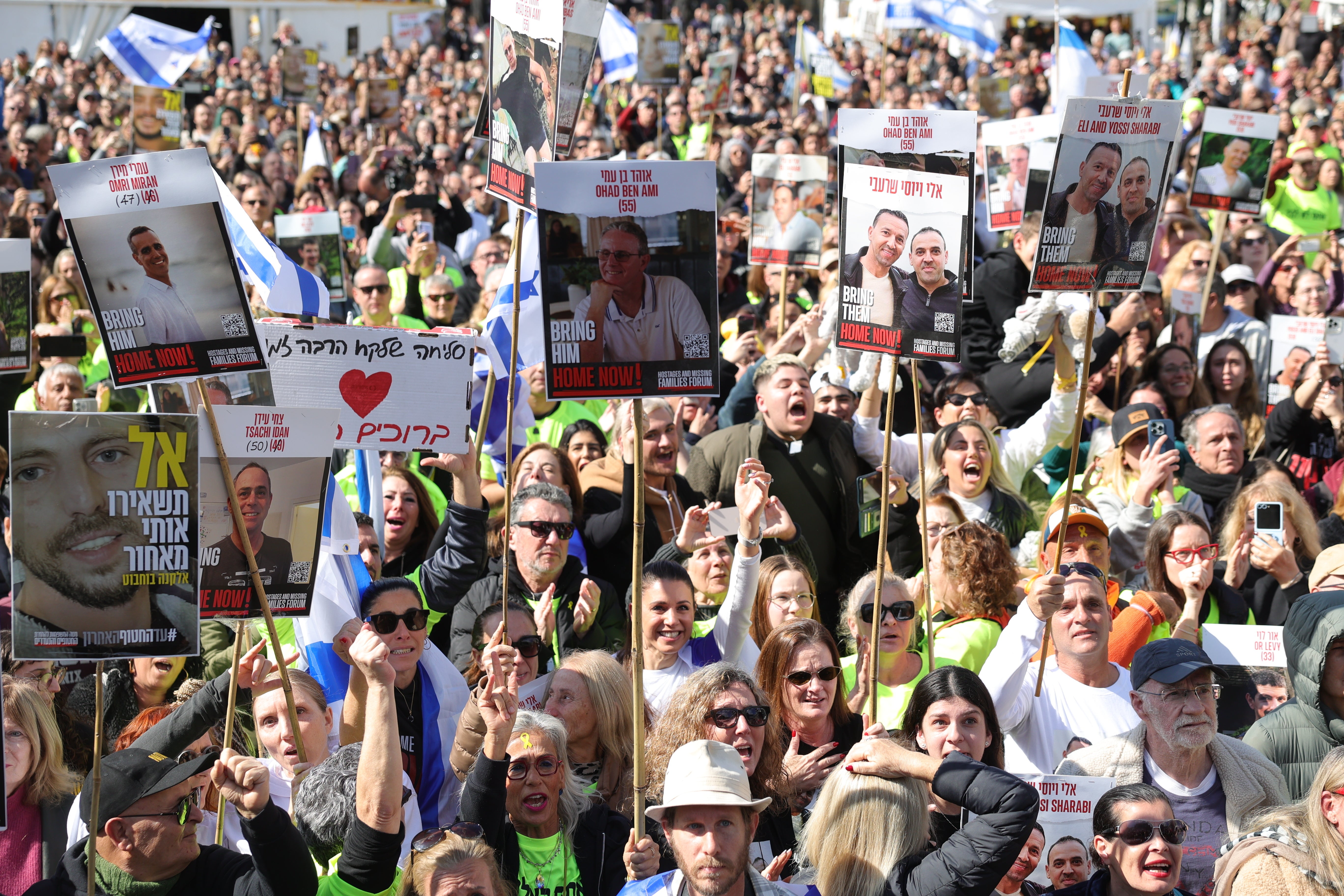 People watch a live stream on a big screen reporting on the release of the three Israeli hostages Eli Sharabi, Or Levy and Ohad Ben Ami on Saturday