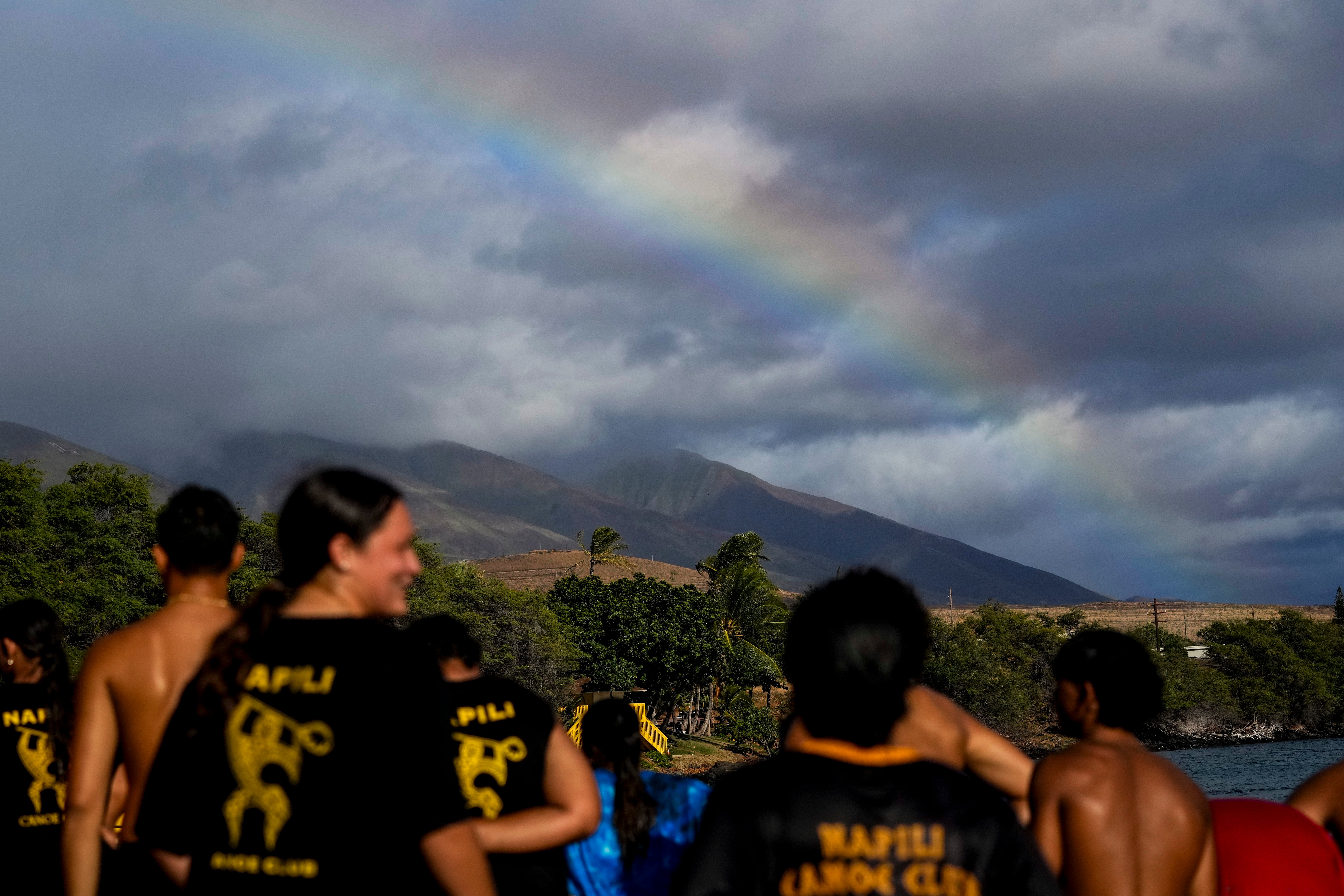 A rainbow forms as members of the Napili Canoe Club run on the beach on Monday, July 8, 2024, at Hanakao’o Park