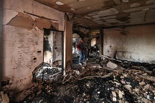 Palestinians inspect the building for damage following an Israeli attack.