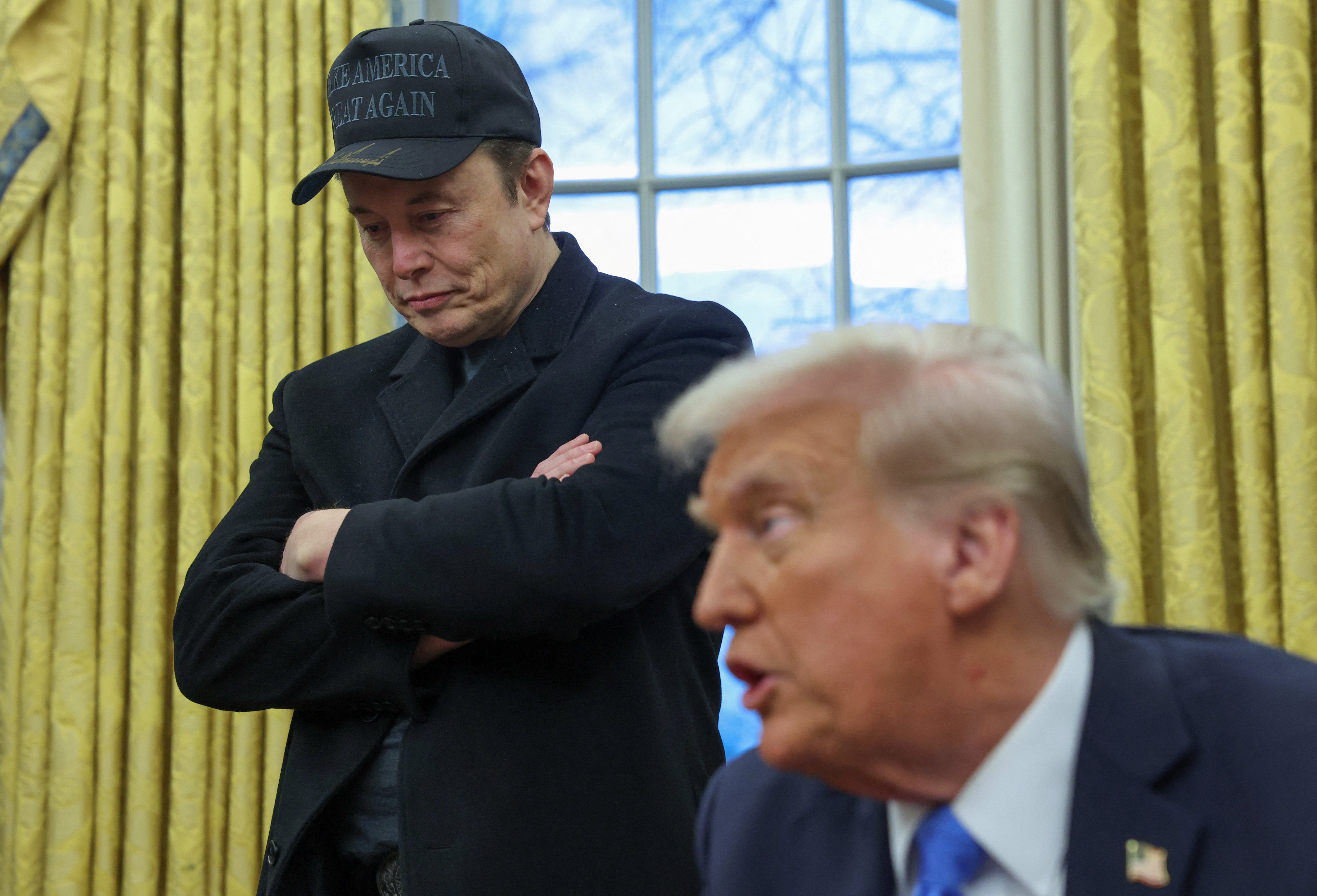 Elon Musk listens to U.S. President Donald Trump speak in the Oval Office of the White House in Washington, D.C., U.S., February 11, 2025