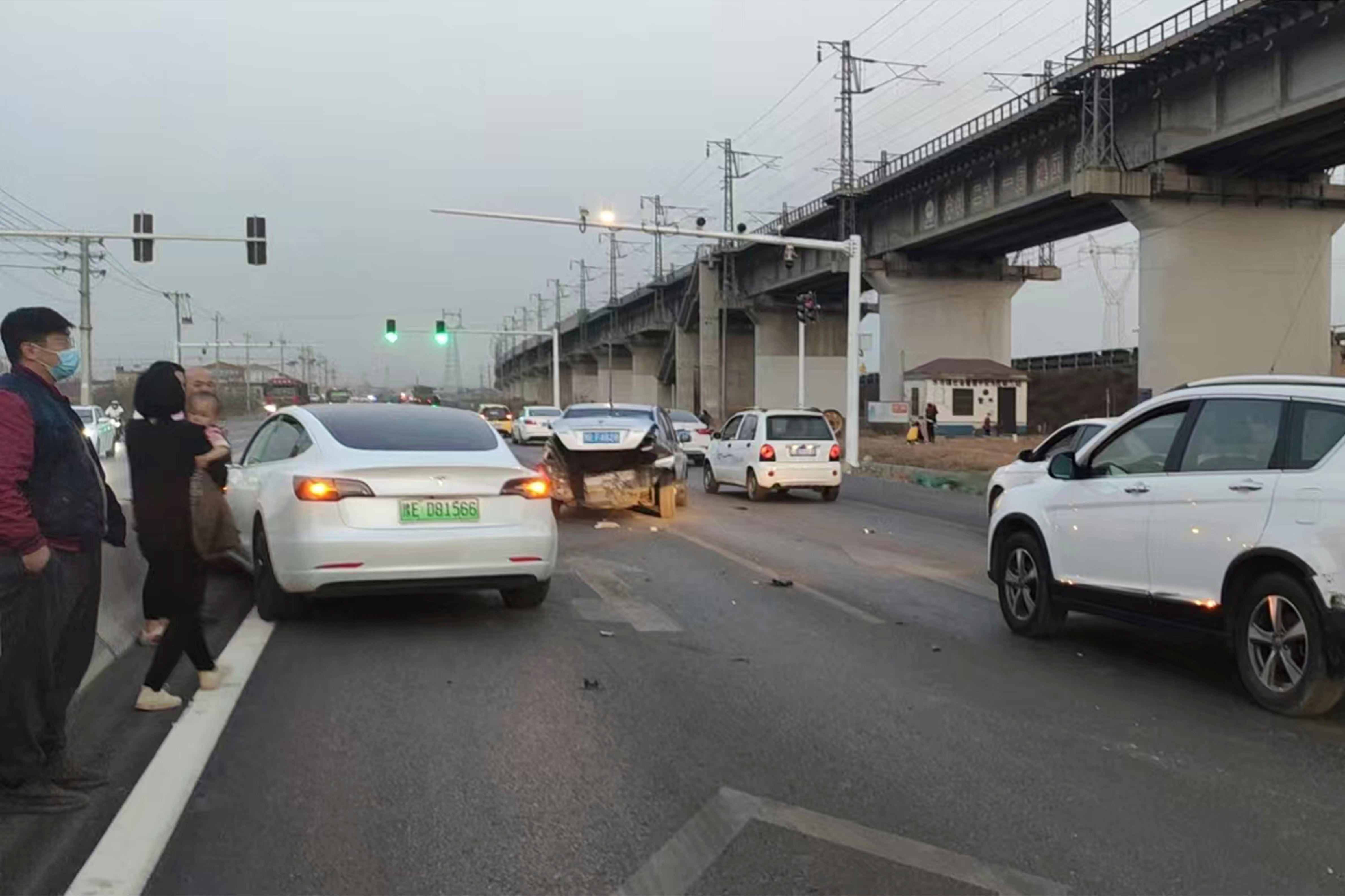 This photo provided by Zhang Yazhou shows her damaged Tesla Model 3, left, which her father was driving