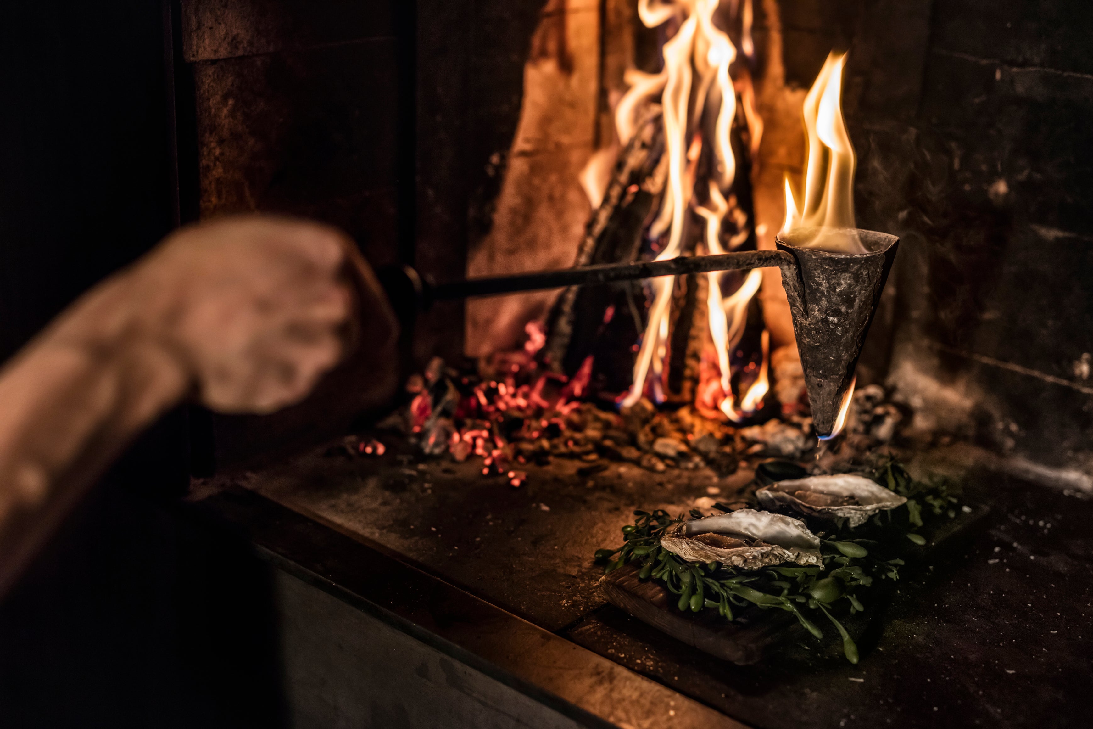 Oysters are flambadou-fired, dripping with molten beef fat for a rich, smoky finish
