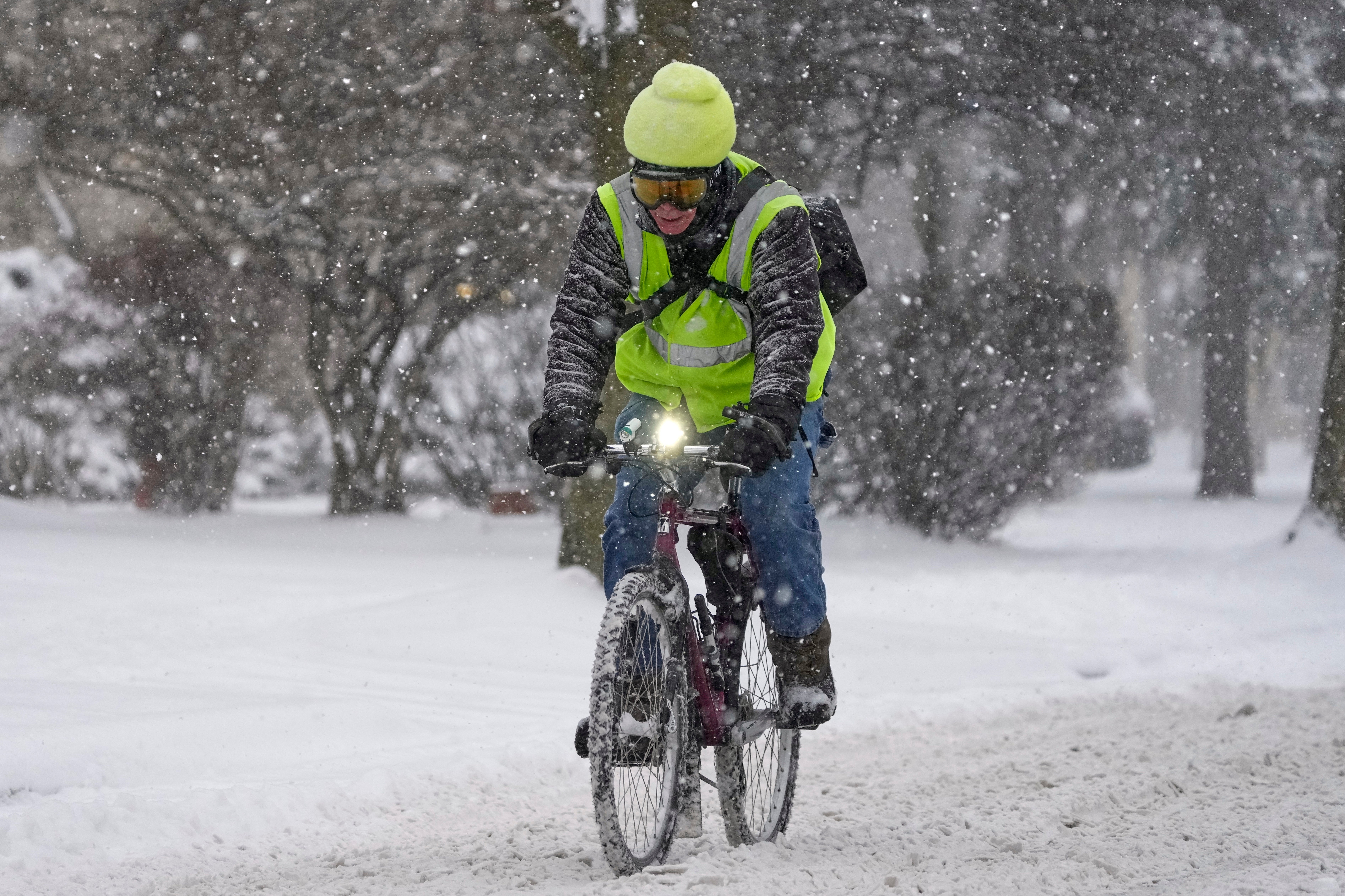 A biker makes their way on a street during a snowfall Wednesday