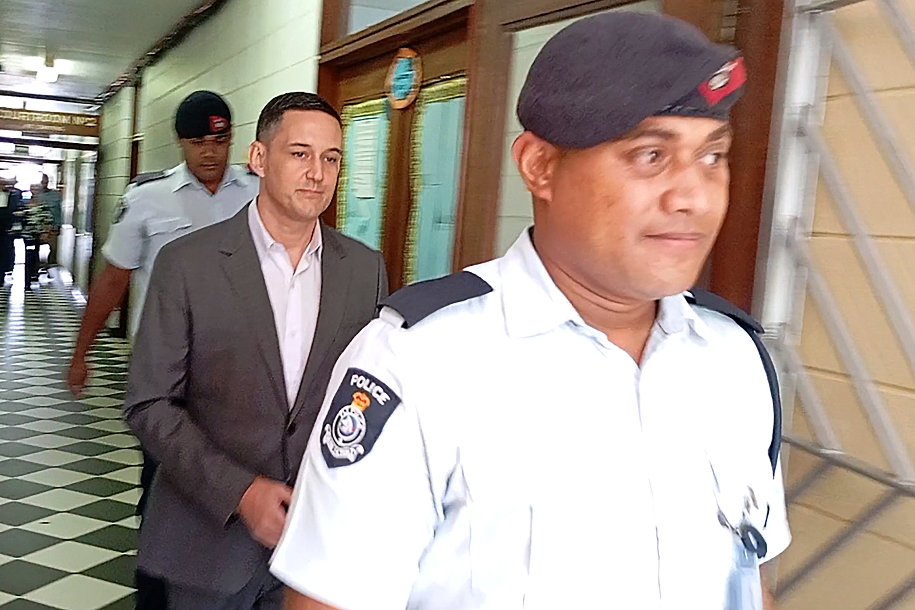 Bradley Robert Dawson, center, is escorted by police at the High Court in Lautoka, Fiji, on Tuesday, Feb. 11