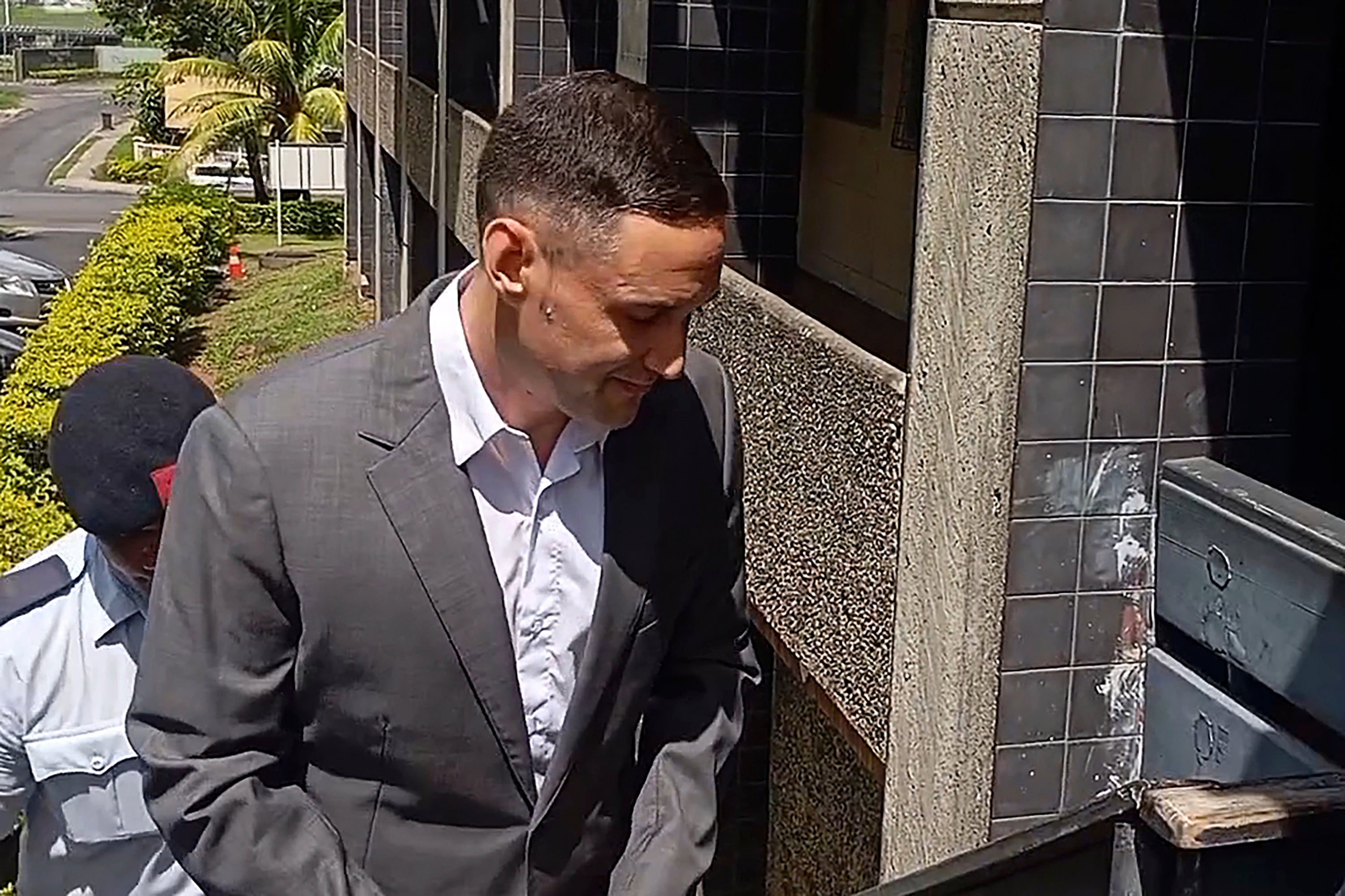 Bradley Robert Dawson, right, is escorted by police at the High Court in Lautoka, Fiji, on Tuesday, Feb. 11