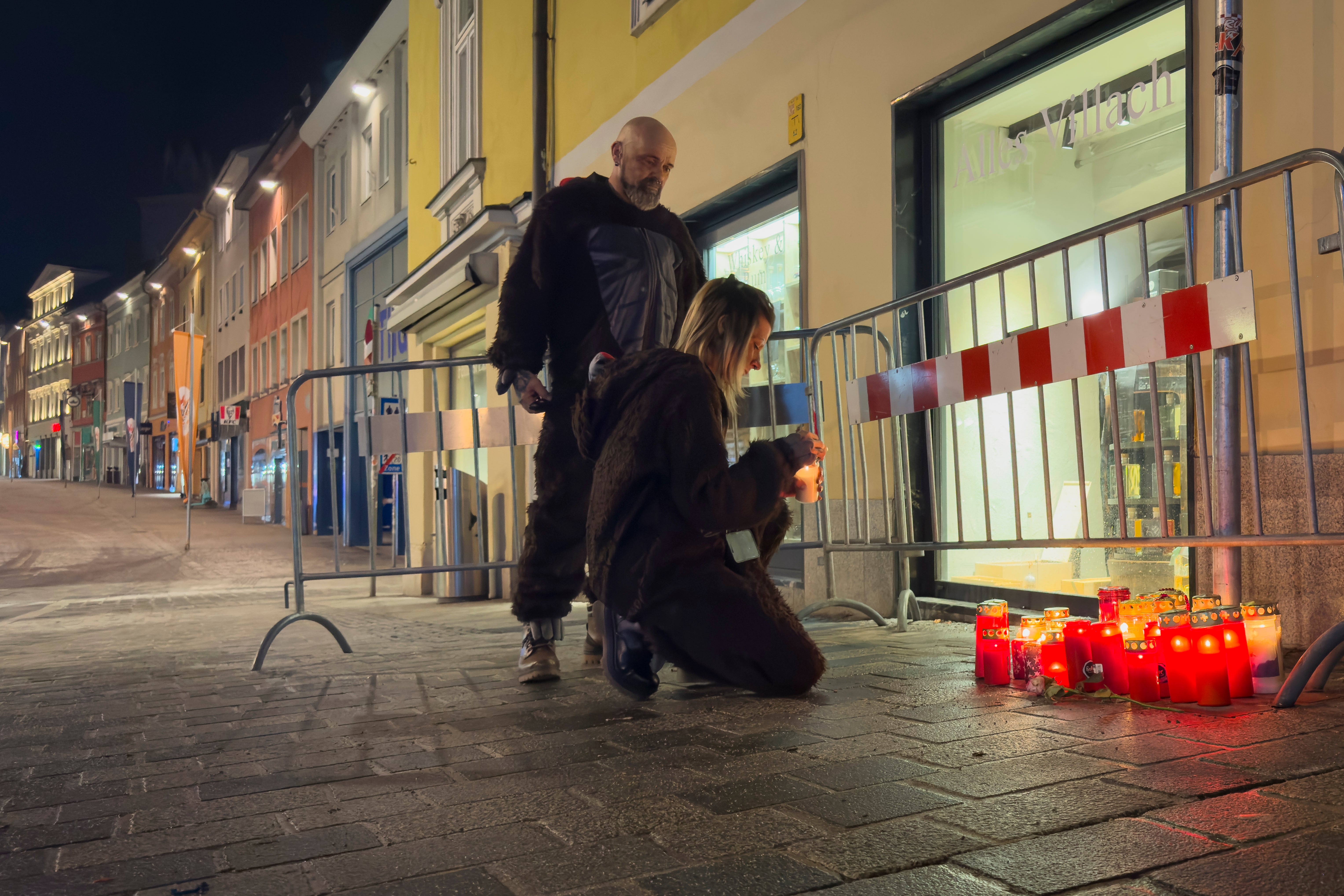 A person lights a candle at the site of a stabbing attack in Villach