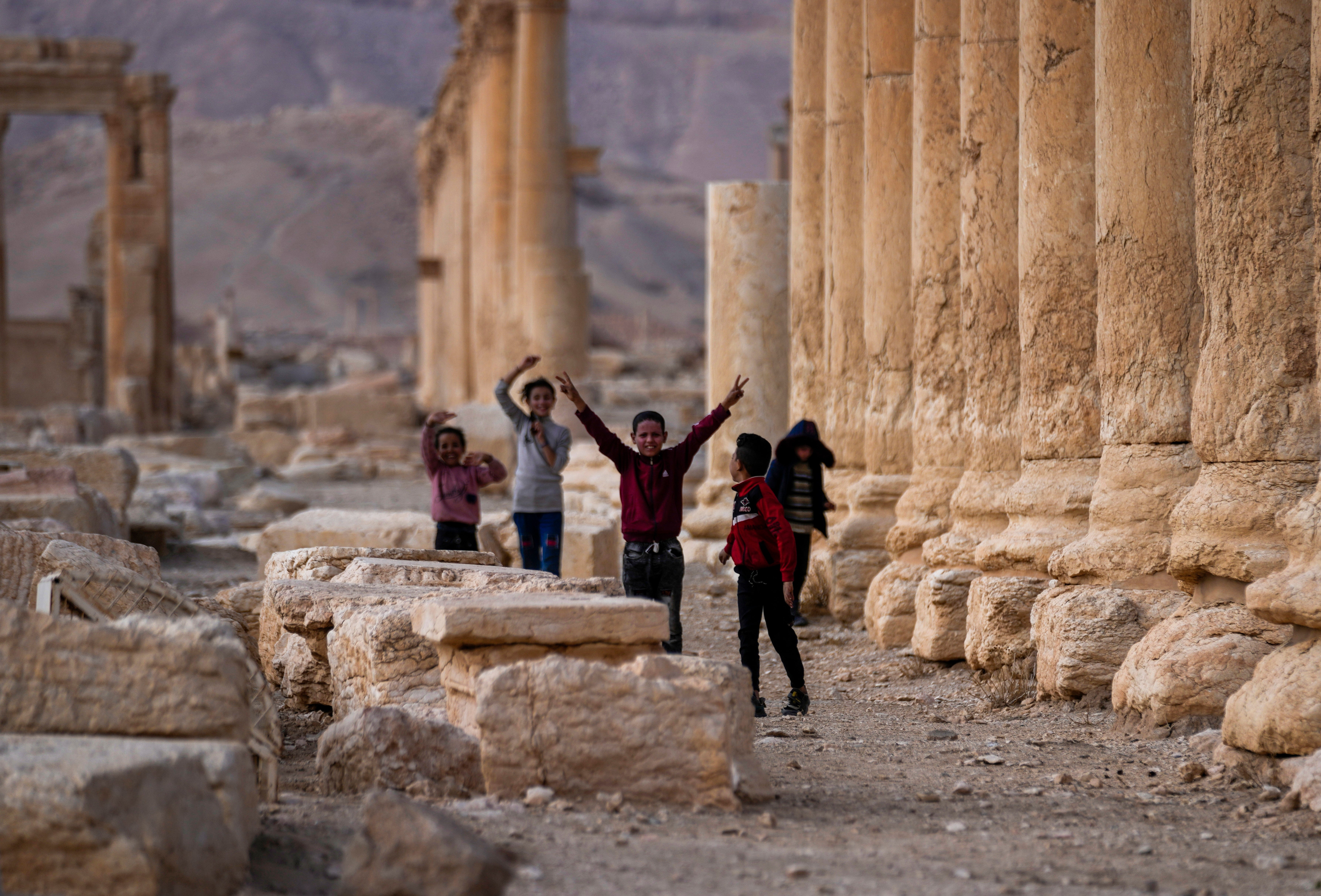 Children play, with one raising the V sign, at the ancient city of Palmyra, Syria, Saturday, Jan. 25