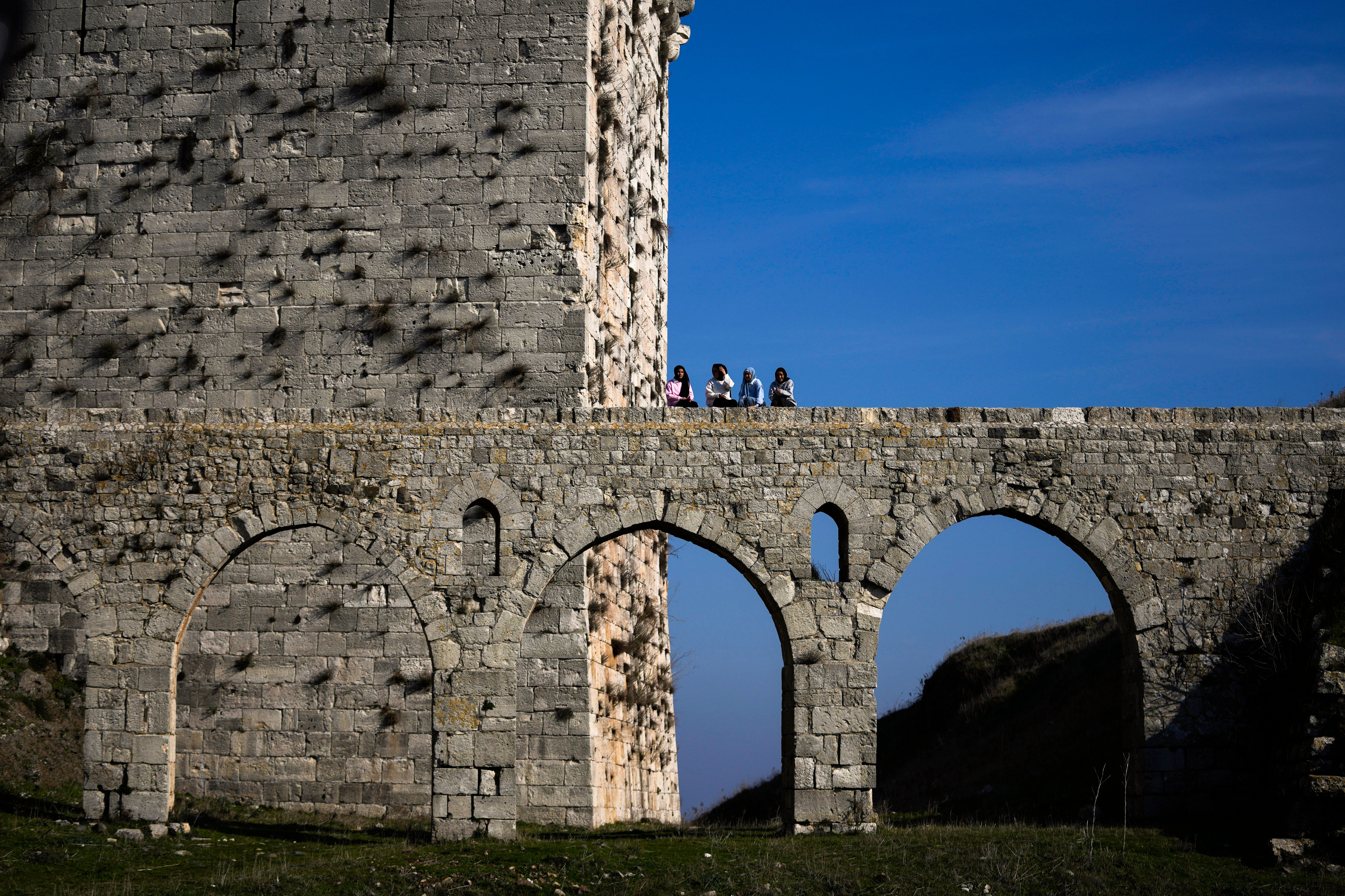 Women sit on a bridge at Krak des Chevaliers on the outskirts of Homs, Syria, Sunday, Jan. 26