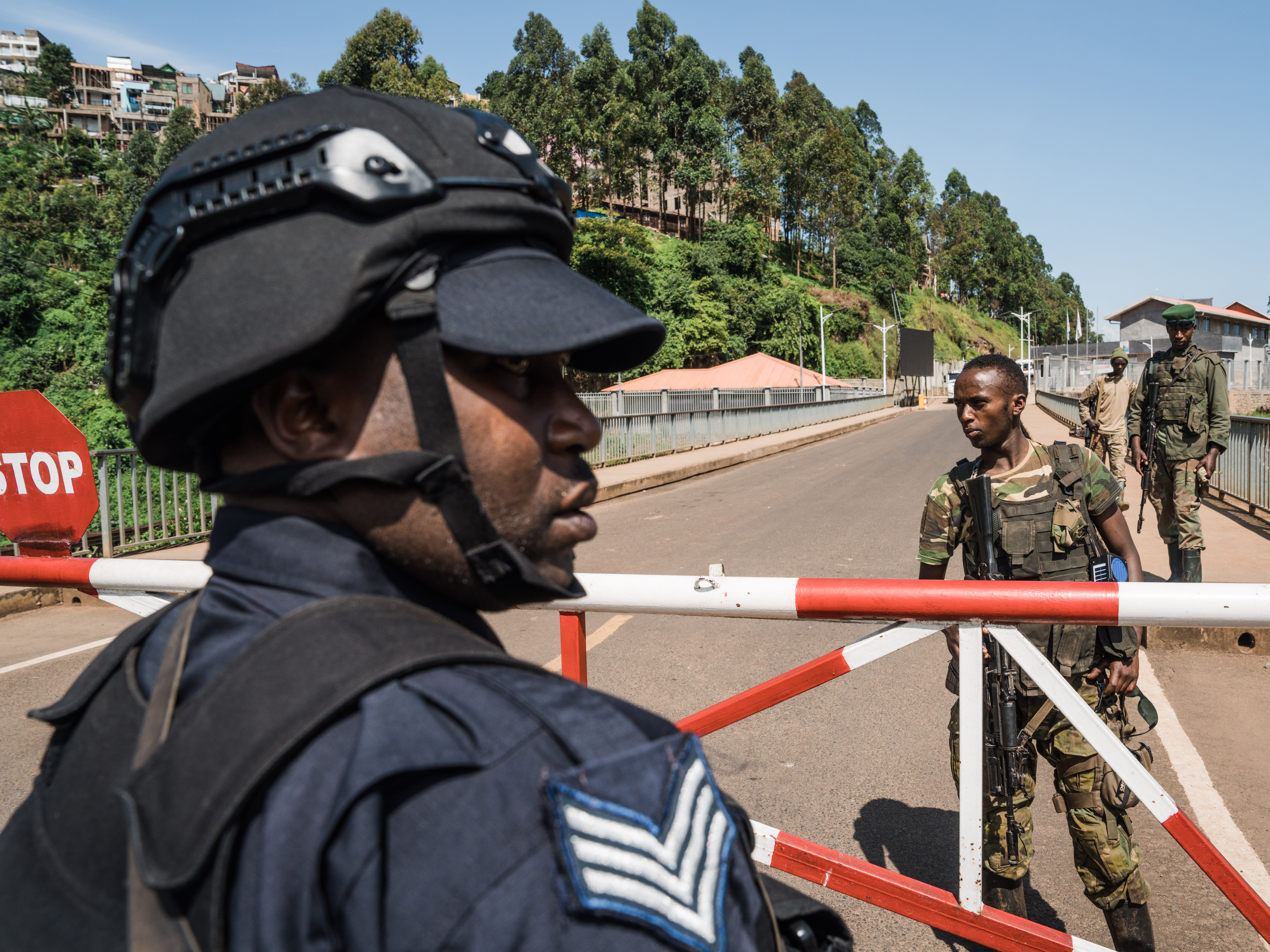 A Rwandan police officer watches as rebels approach