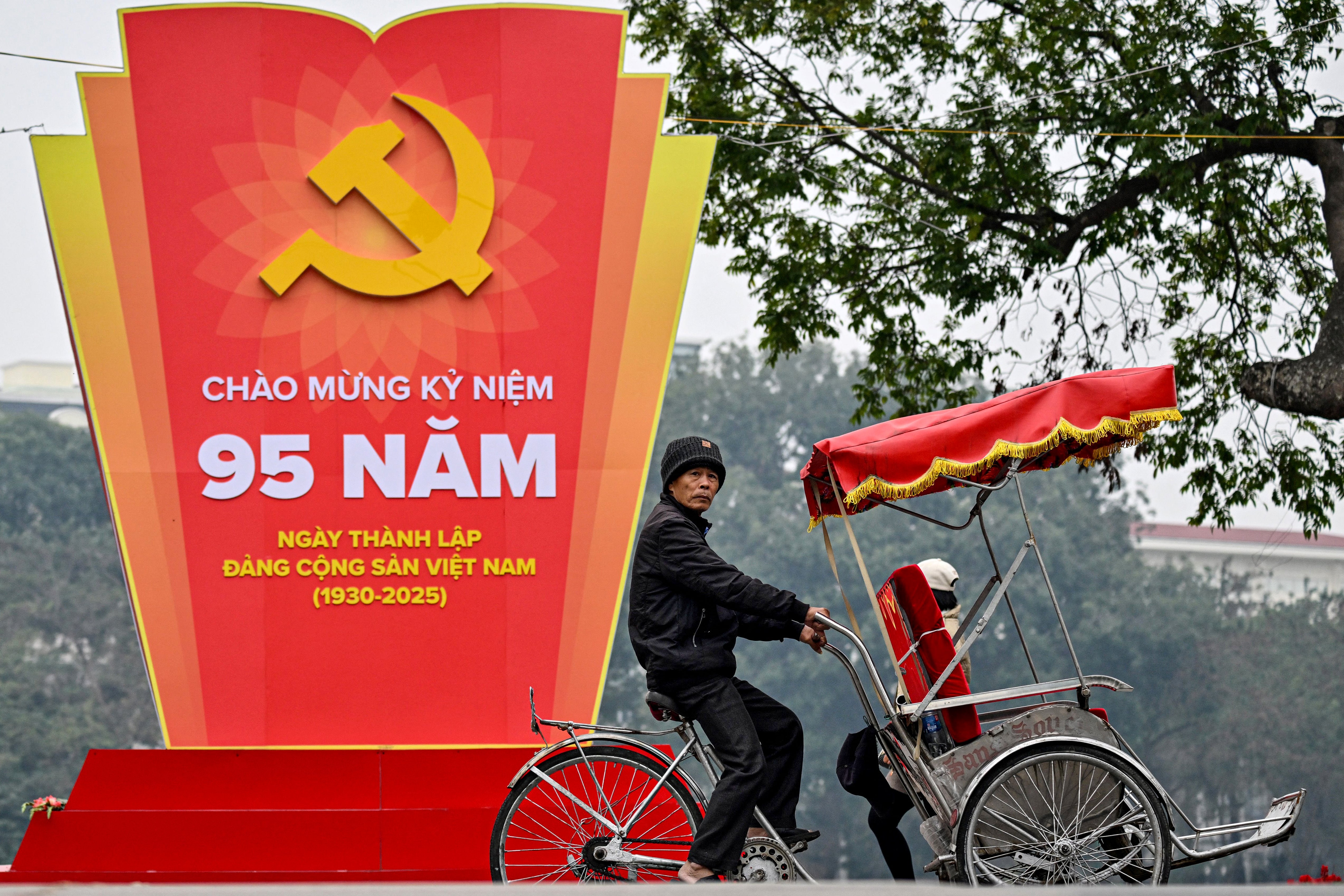 A man rides his cycle past a billboard advertising the 95th anniversary of the founding of the Communist Party of Vietnam