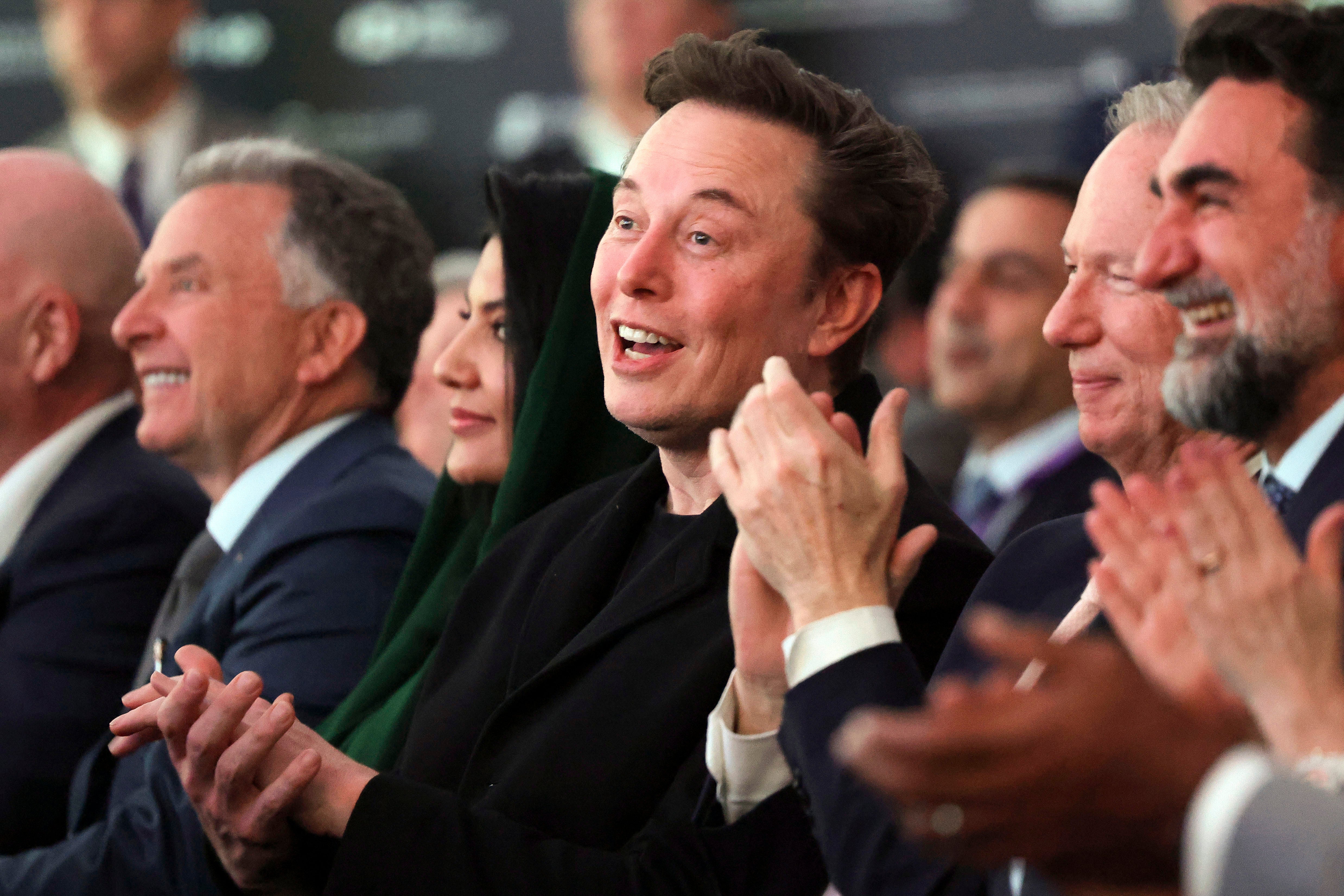 Elon Musk listens as Donald Trump speaks in Miami on February 19