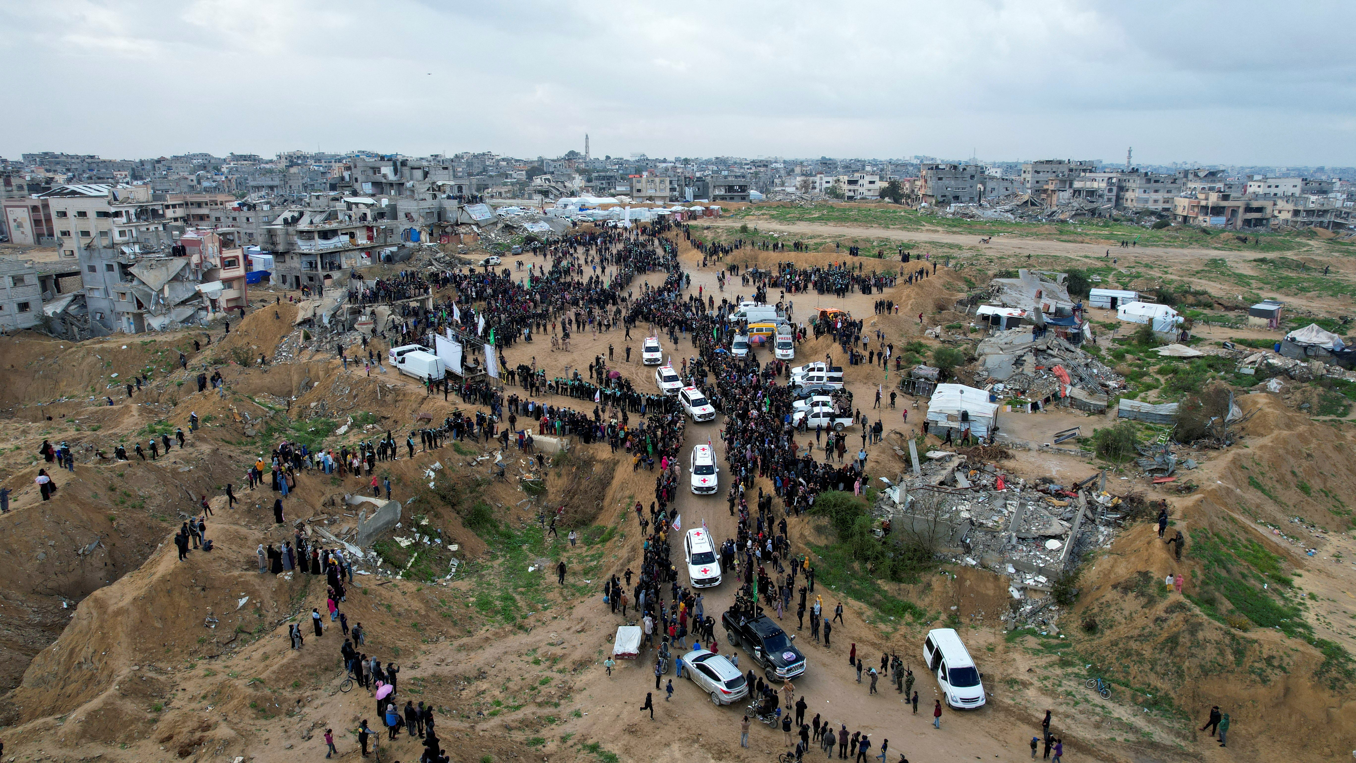 A drone view shows Palestinians and militants gathering around Red Cross vehicles as Hamas handed over the bodies of deceased hostages