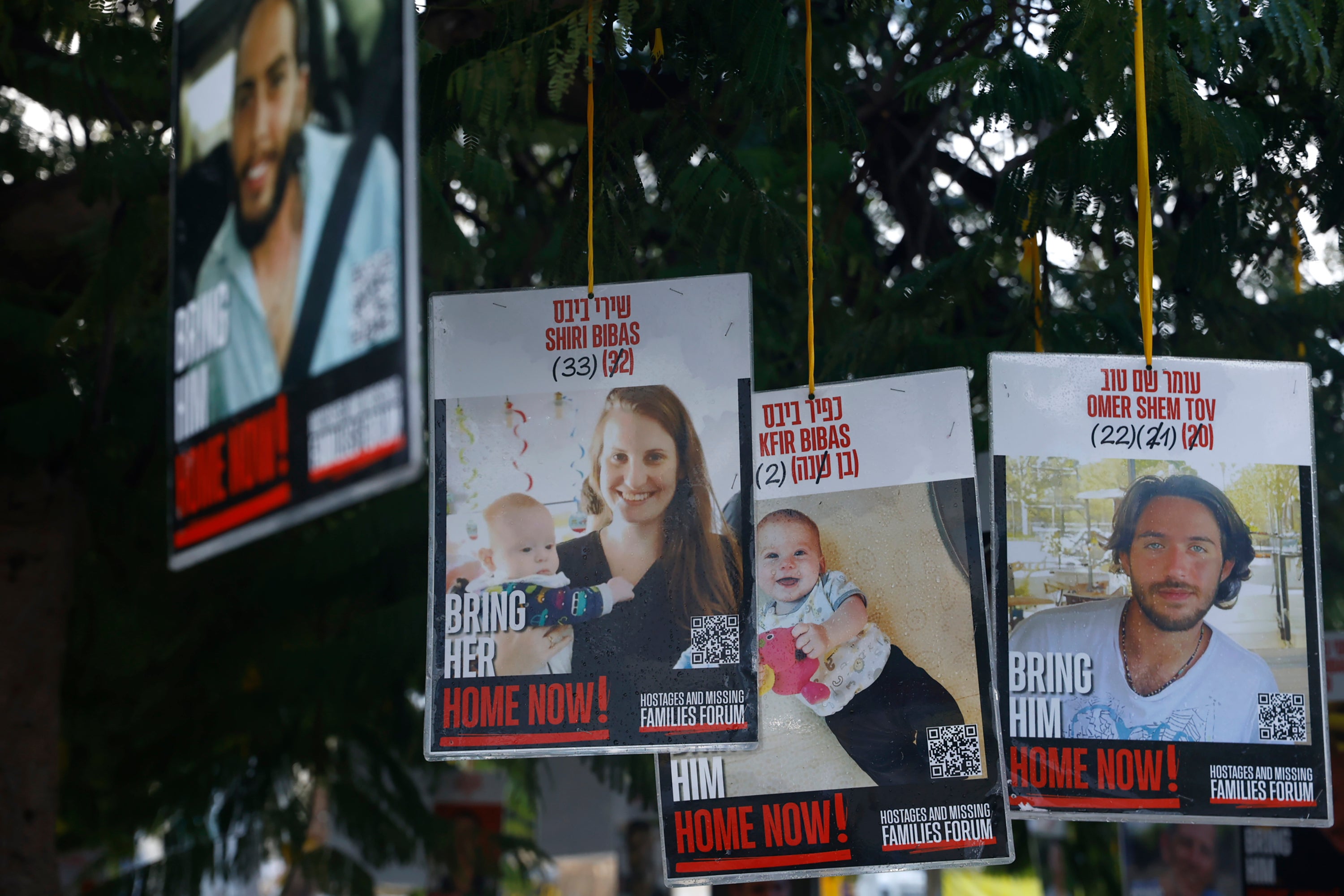Posters of hostages Shiri Bibas, Kfir Bibas and Omer Shem Tov are displayed in Hostages Square in Tel Aviv