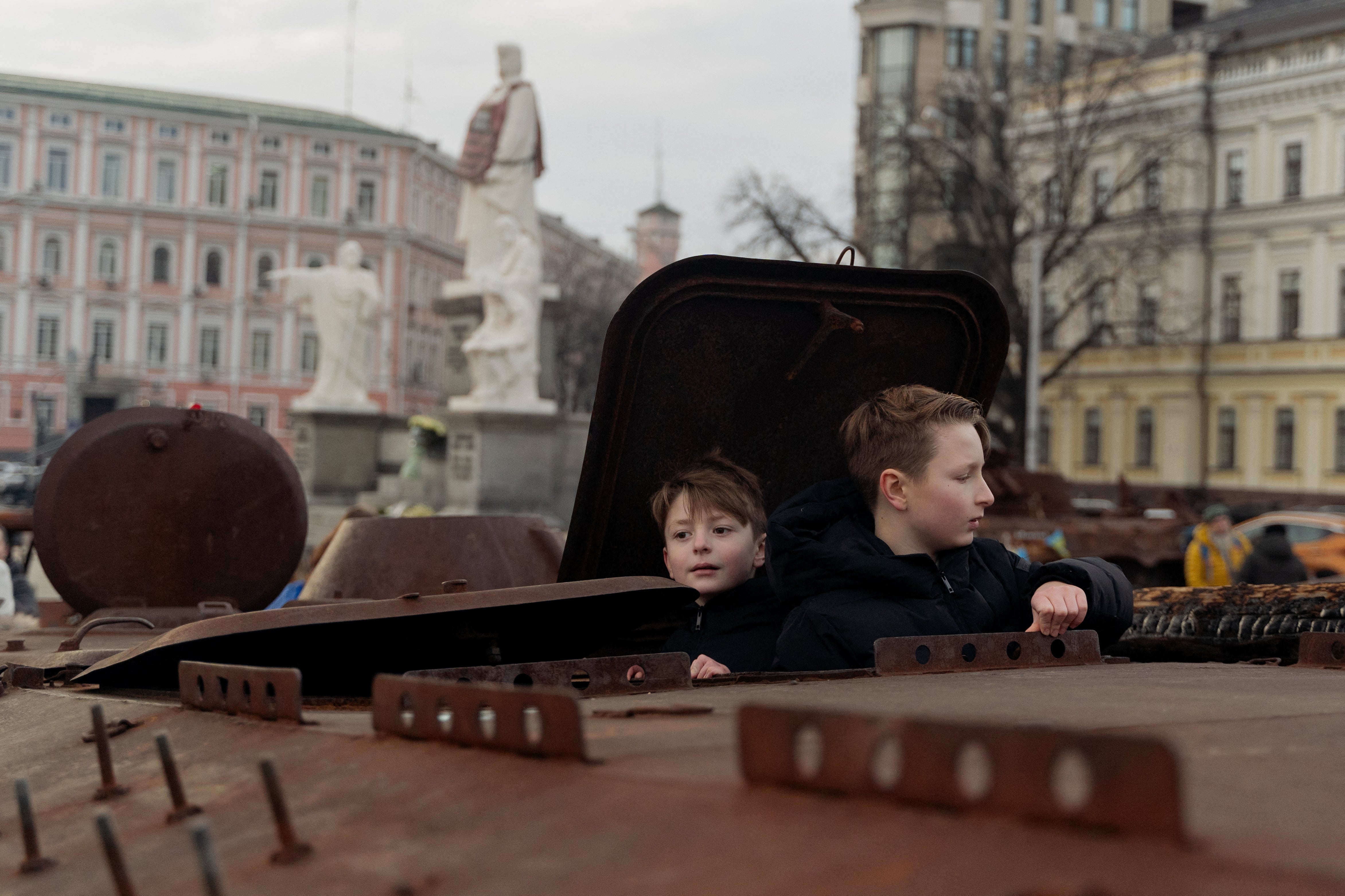 Children climb on a destroyed Russian personnel carrier at an exhibit in Kyiv