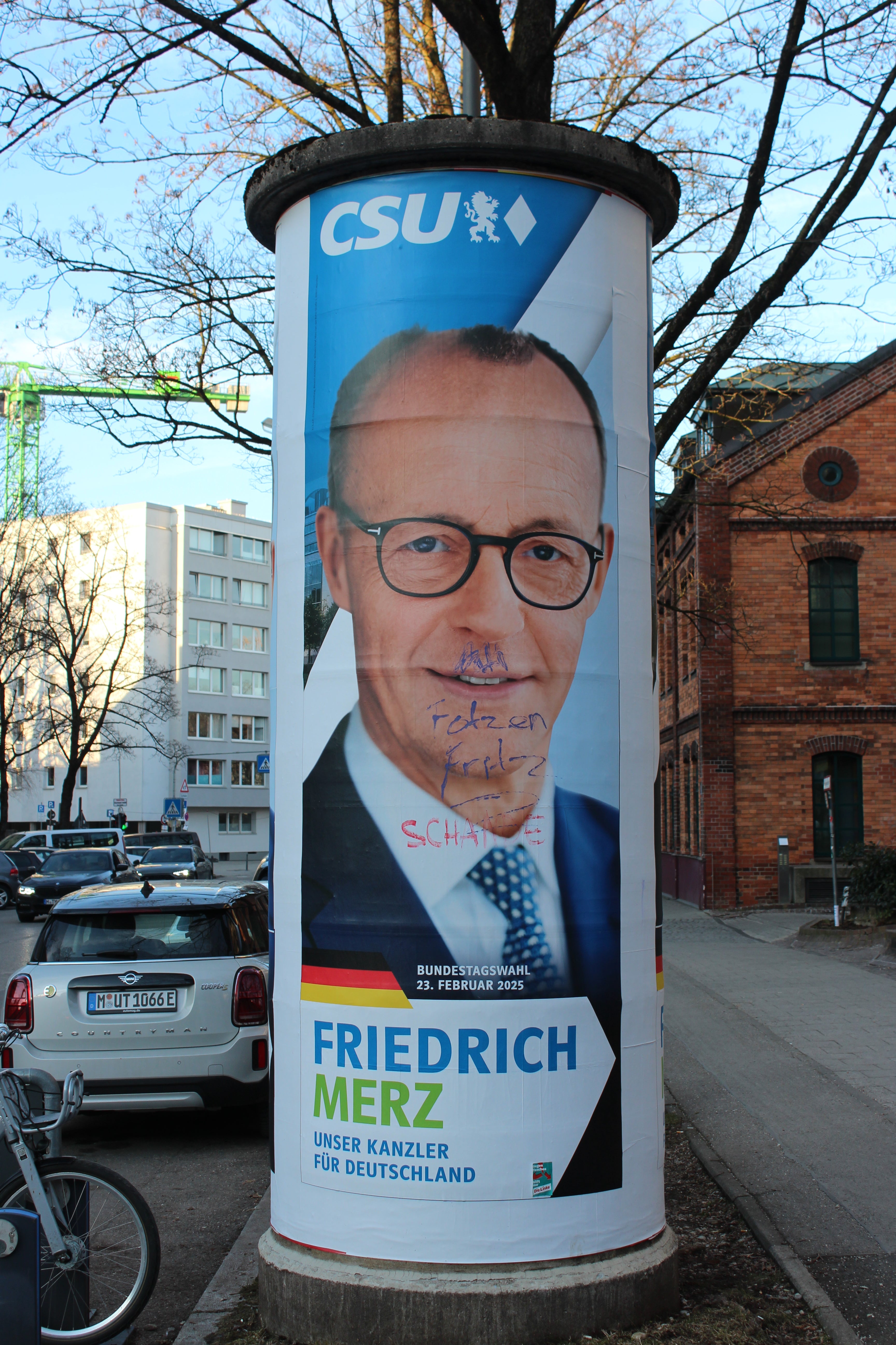 A poster of Friedrich Merz defaced with an Adolf Hitler moustache near the scene of the Munich attack