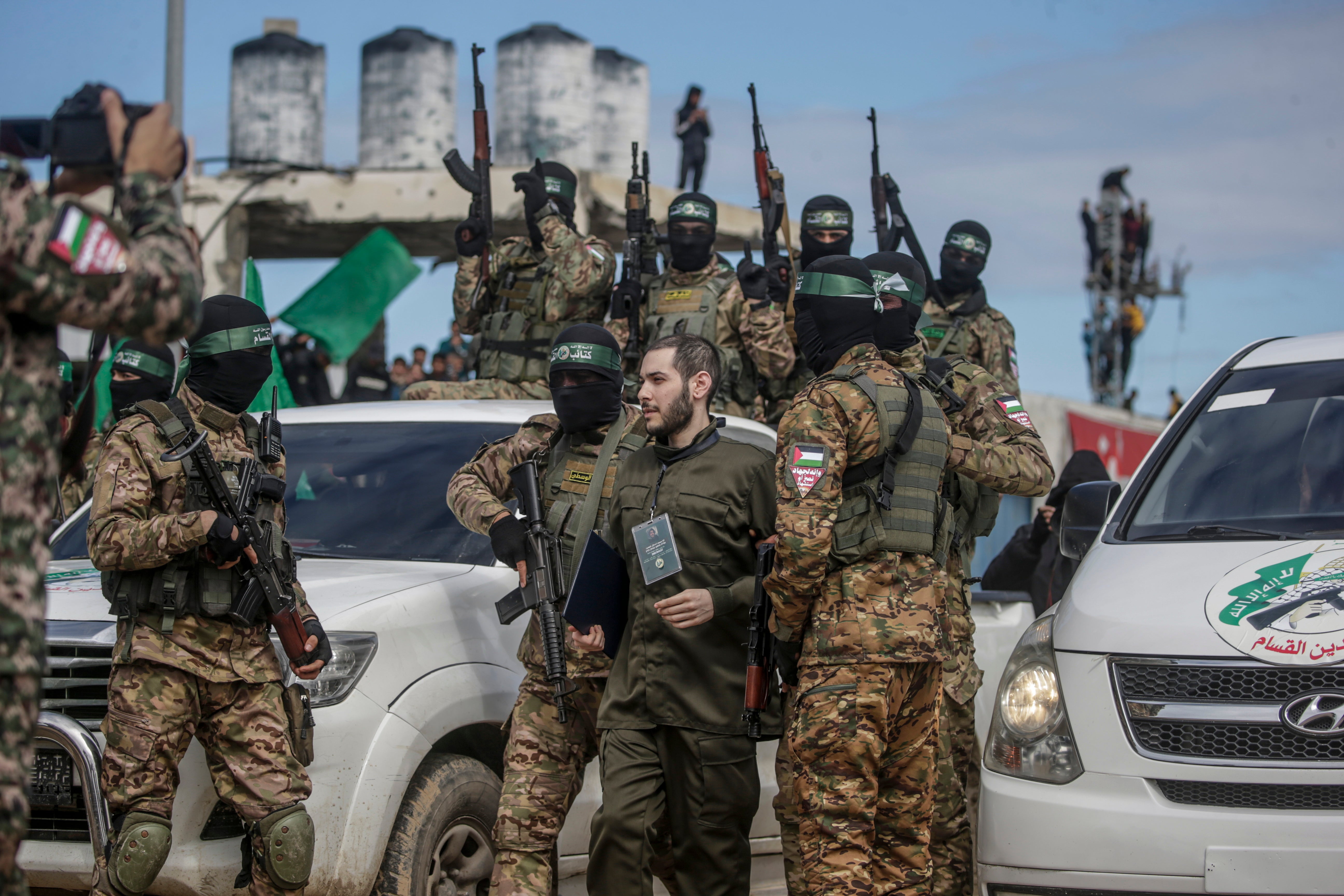 Fighters from Hamas’ Izz ad-Din al-Qassam Brigades escort Israeli hostage Eliya Cohen before handing him over to the Red Cross in Al Nusairat refugee camp