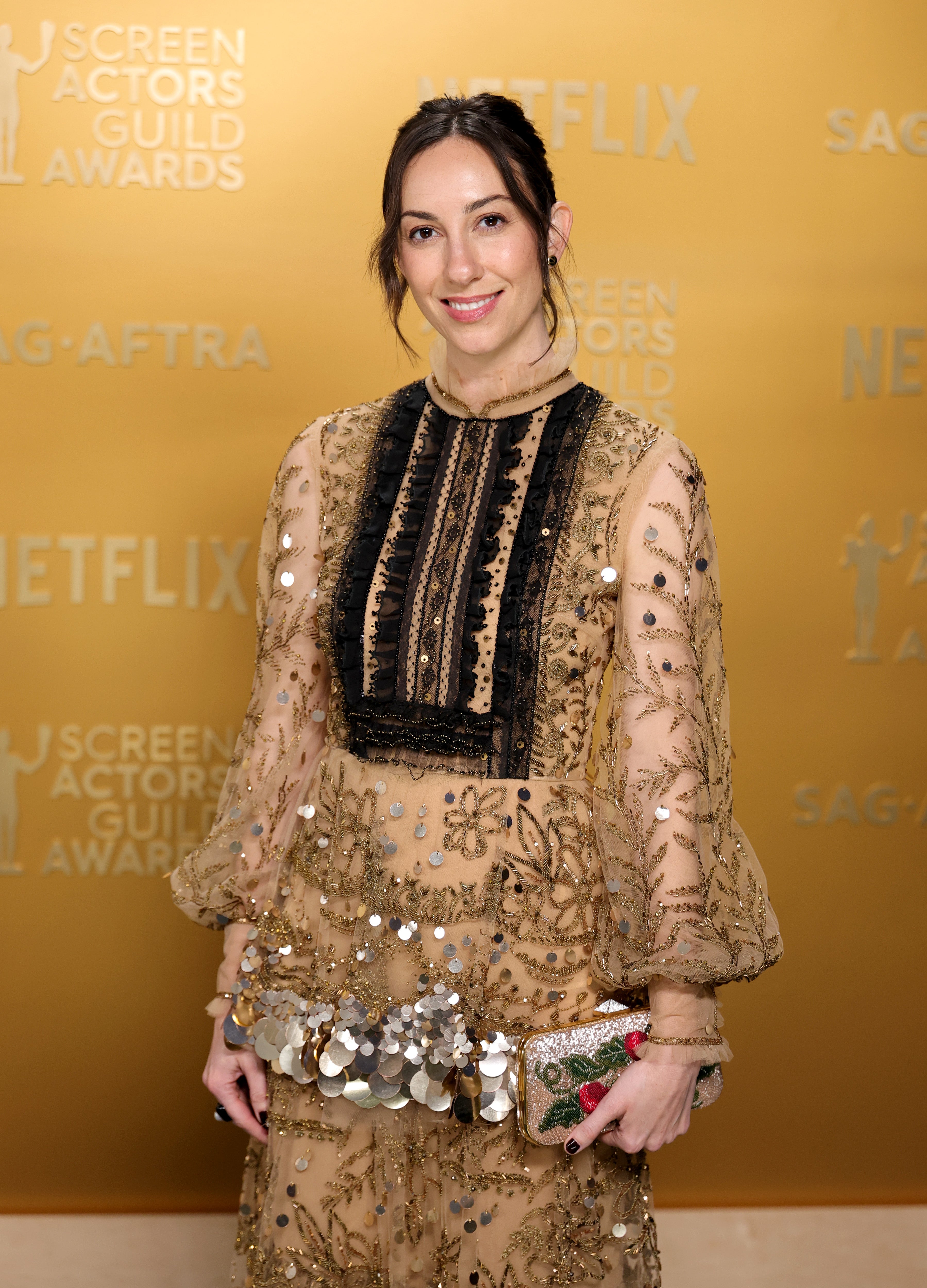 The director wore a Valentino dress, but the busy outfit clashed against the gold background.