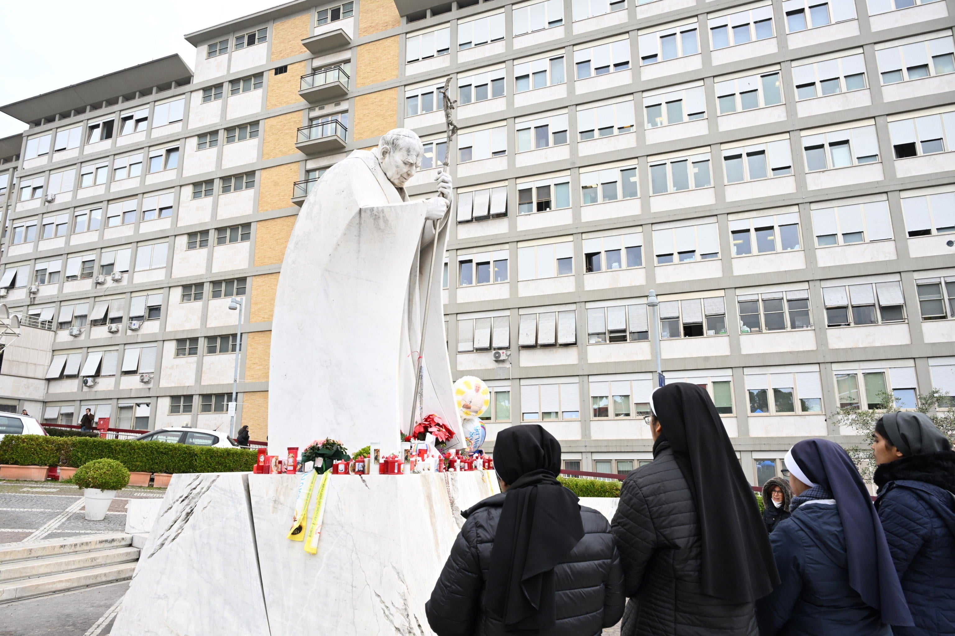 Nuns pray before the statue of late Pope John Paul II outside the Agostino Gemelli Hospital where Pope Francis was hospitalised in Rome