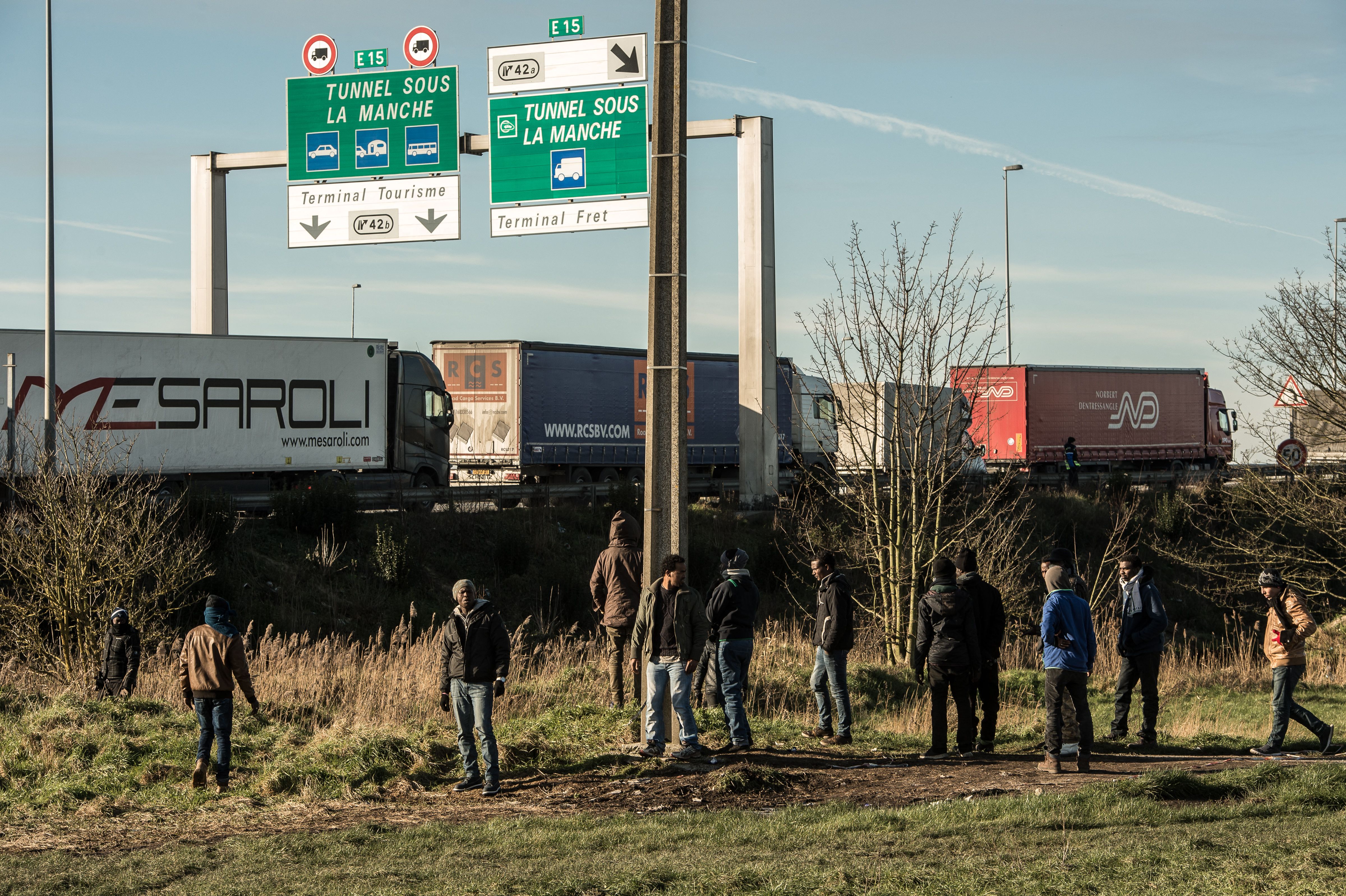 Migrants stand near the A16 motorway near the site of the Eurotunnel in Coquelles, near Calais, northern France
