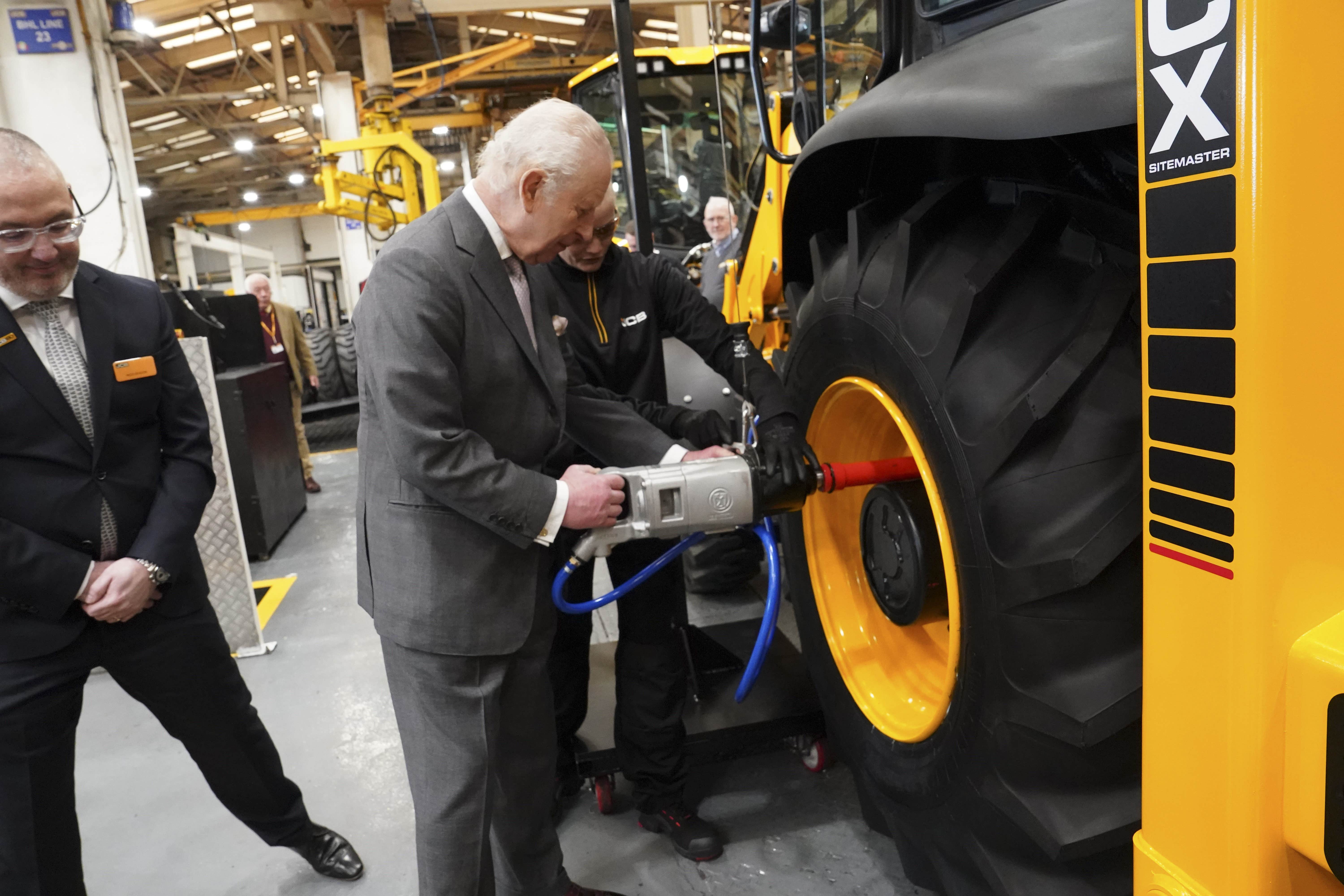 The King fits a tyre to a backhoe loader (Arthur Edwards/The Sun/PA)