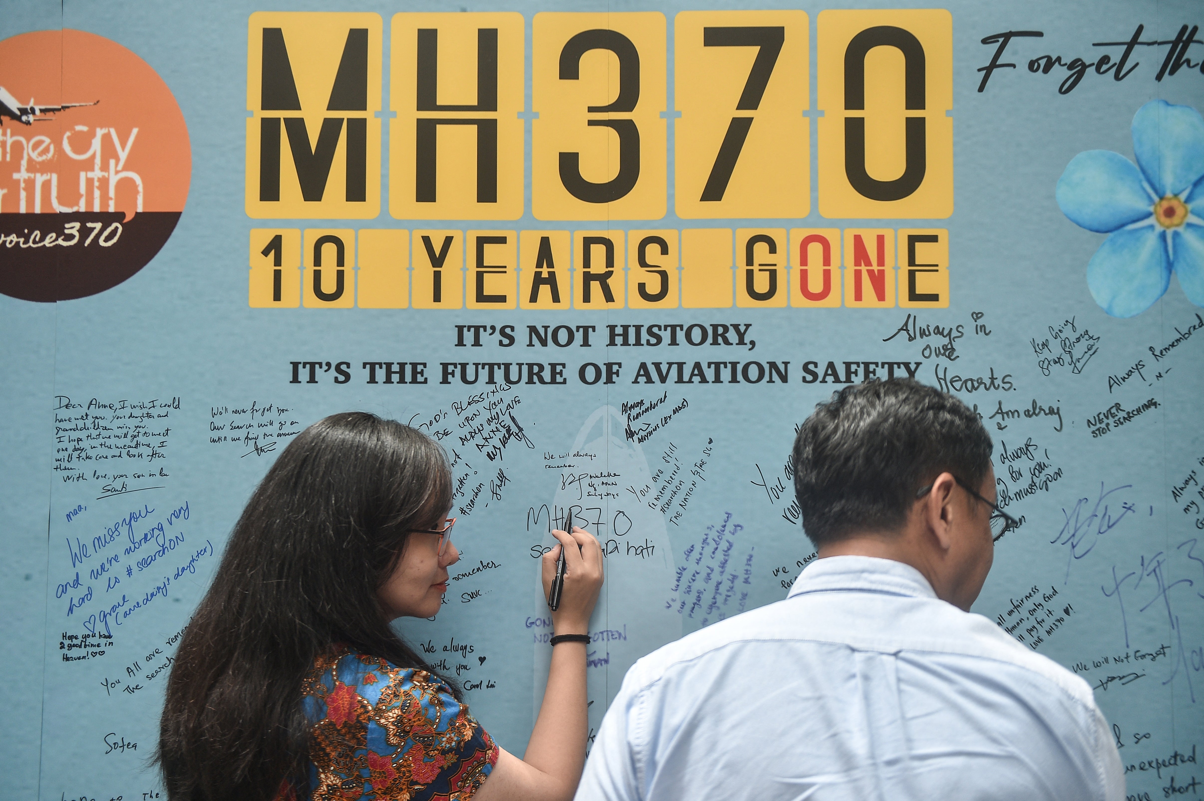 A woman writes a message during an event held by relatives of the passengers and supporters to mark the 10th year since the Malaysia Airlines flight MH370 carrying 239 people disappeared from radar screens on March 8, 2014
