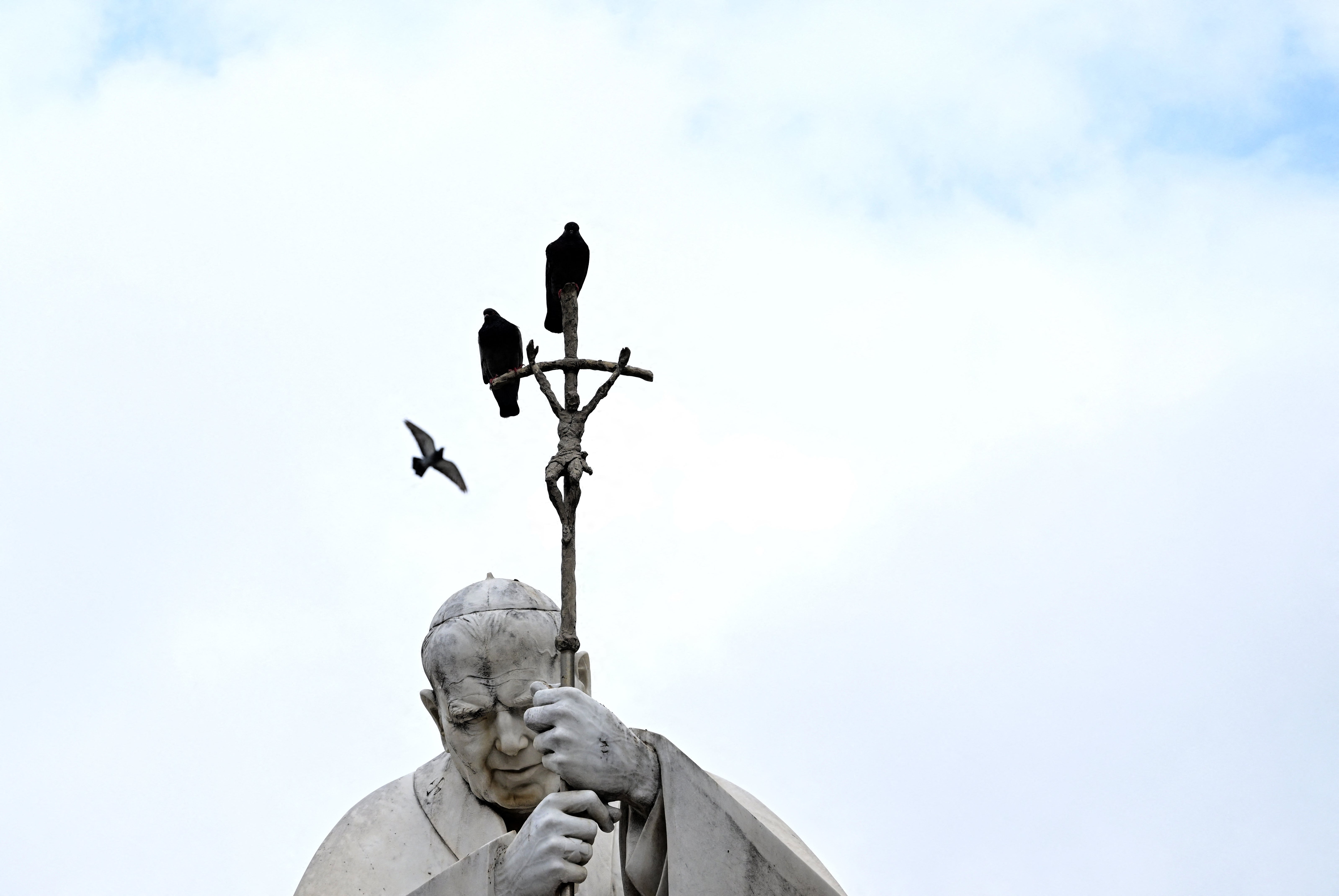Pigeons roost on a statue of Pope John Paul II outside Gemelli hospital, where Francis is being treated