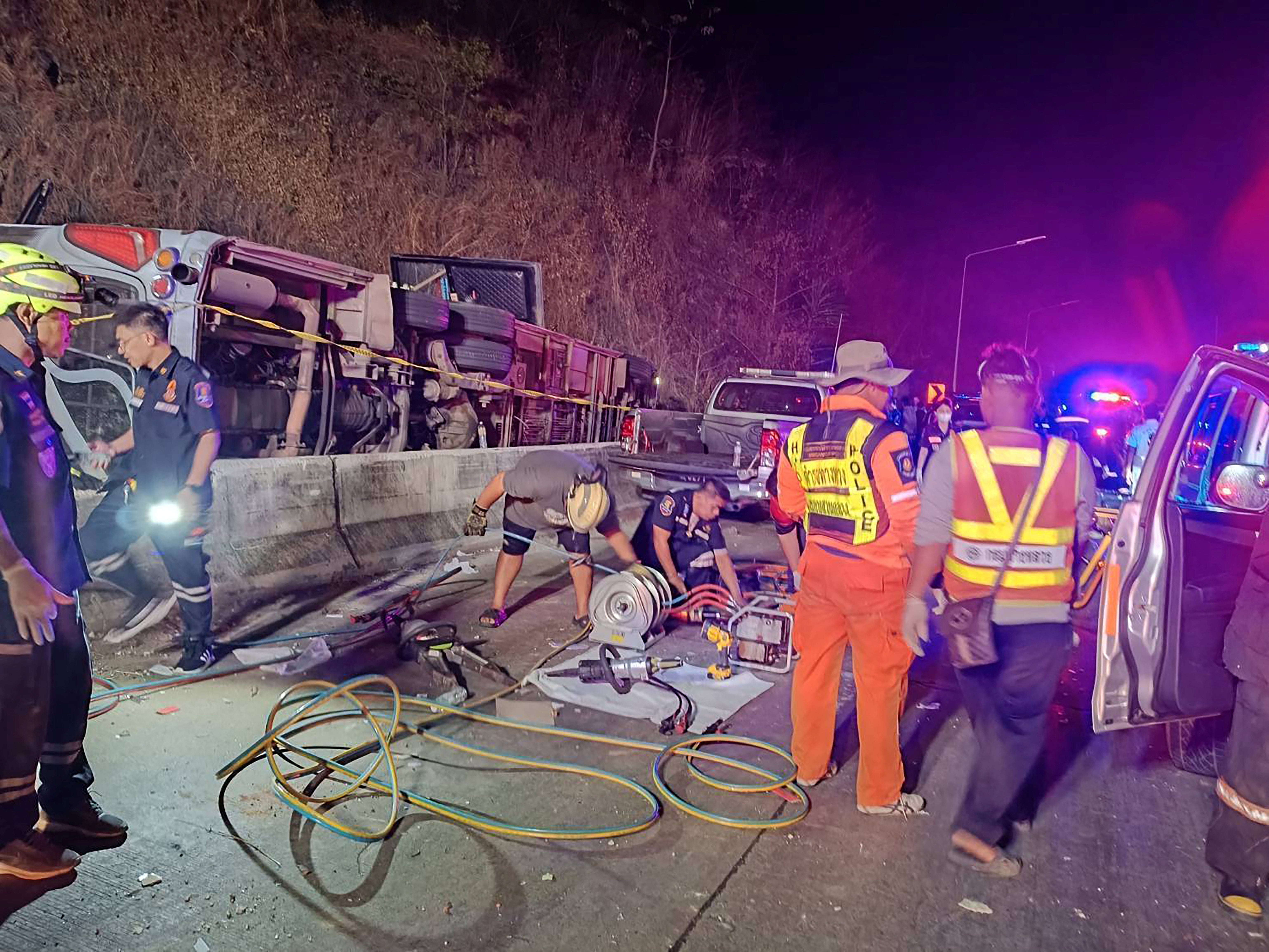 Rescue personnel work to retrieve casualties from an overturned bus, after it lost control and fell into a ditch during its journey from Bueng Kan to Rayong, in Prachinburi province, Thailand