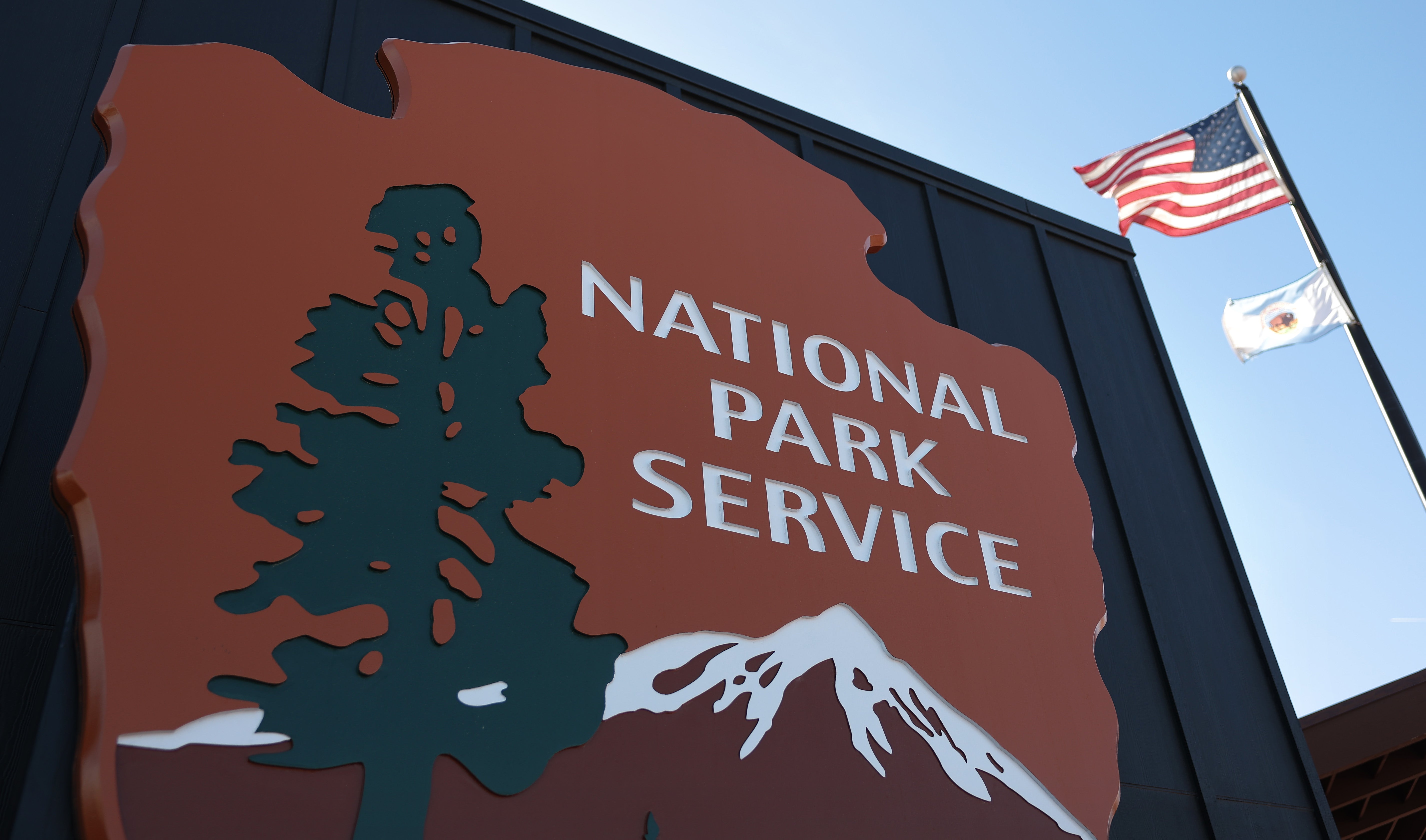 A sign for the National Park Service is seen by flags at Joshua Tree National Park in California
