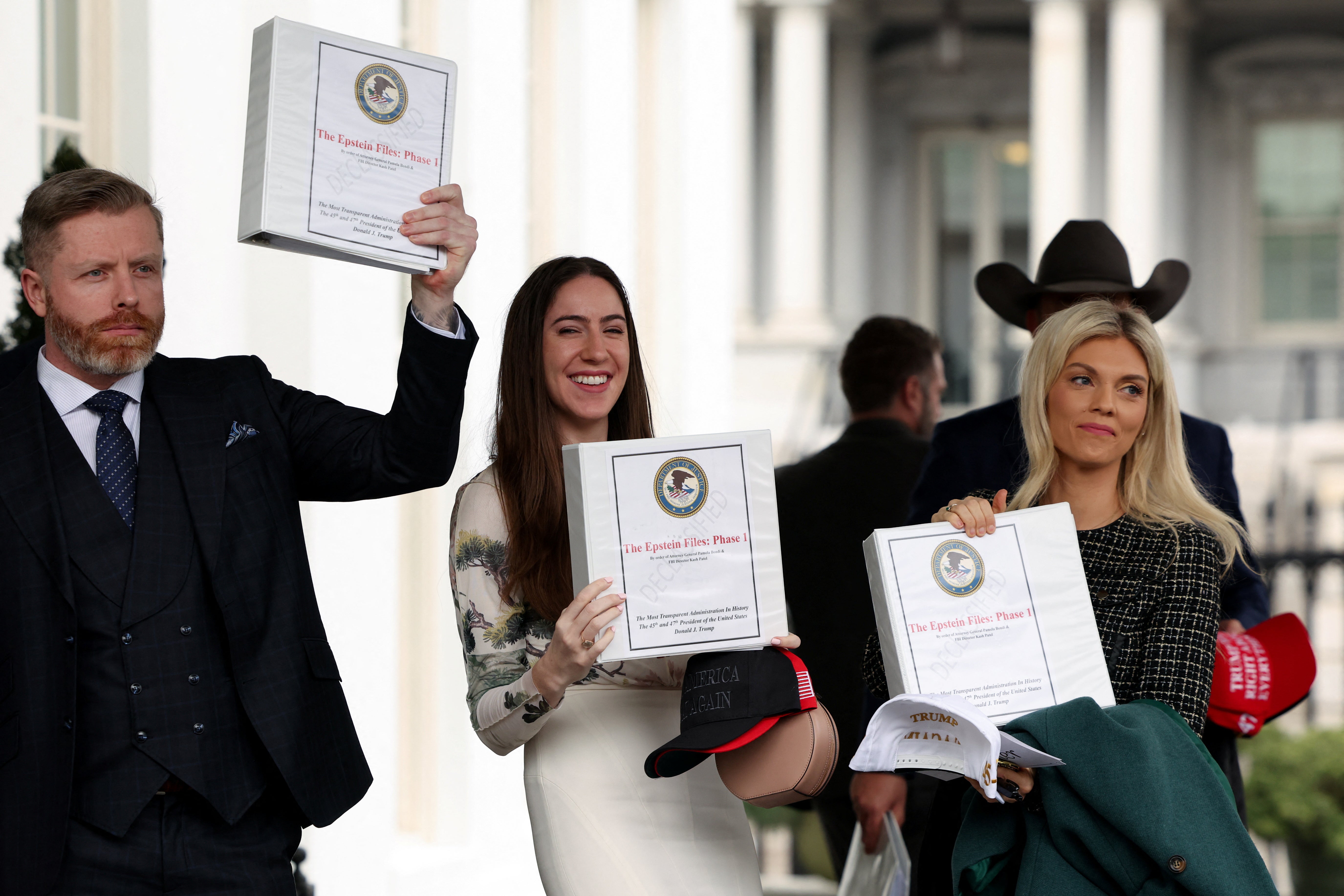 People walk out of the West Wing of the White House with "The Epstein Files: Phase 1" binders, in Washington, D.C., U.S., February 27, 2025