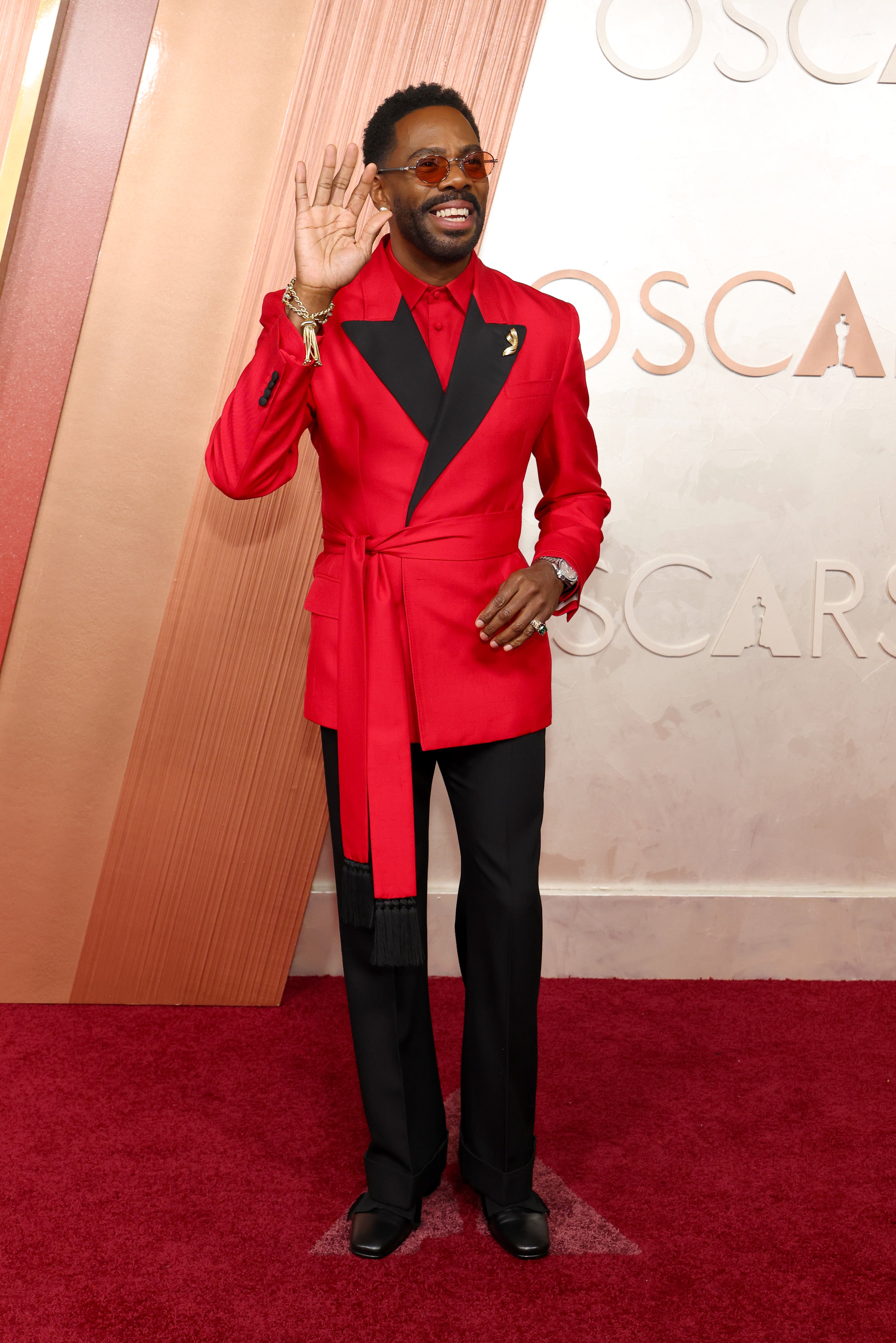 Colman Domingo stunned in a hot red Valentino suit with black lapels and a long waist band. Domingo teamed the tailored ensemble with circular red shades