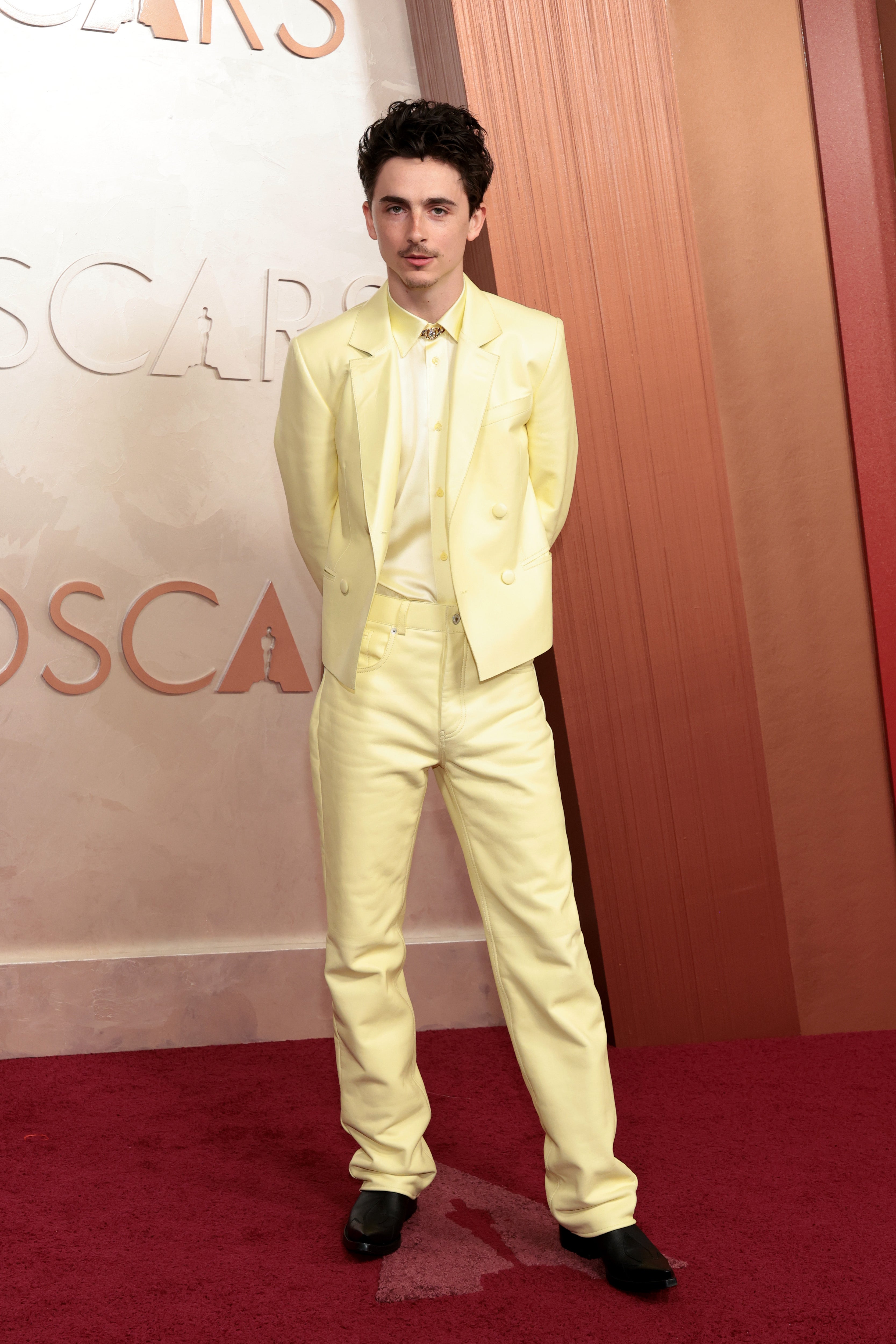 Timothée Chalamet posed outside the Dolby Theater in Los Angeles in a pale yellow satin ensemble by Givenchy, complete with a double-breasted, cropped suit jacket and matching strait-leg pants