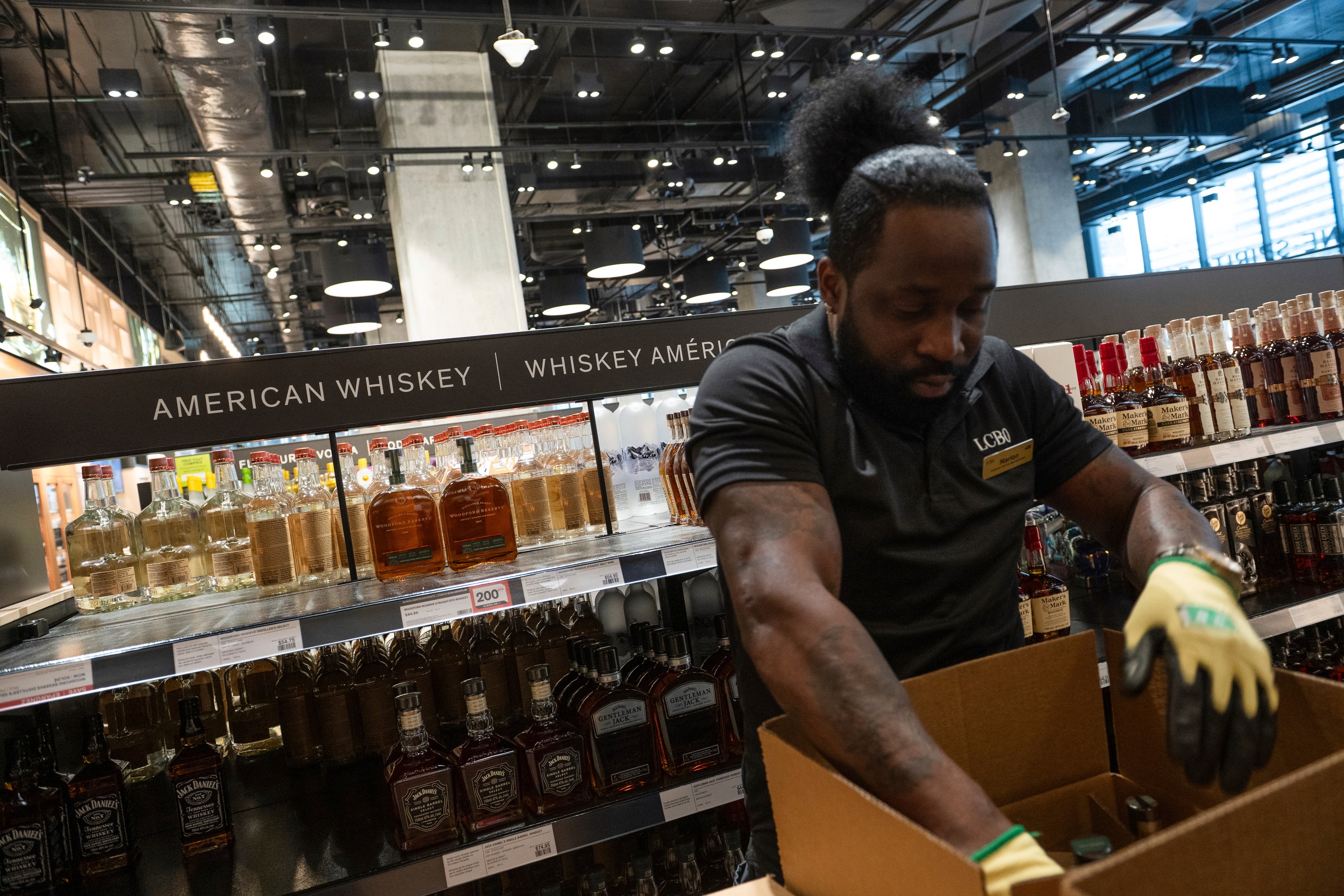 A Liquor Control Board of Ontario employee removes American whiskey from the shelves of a store in Toronto