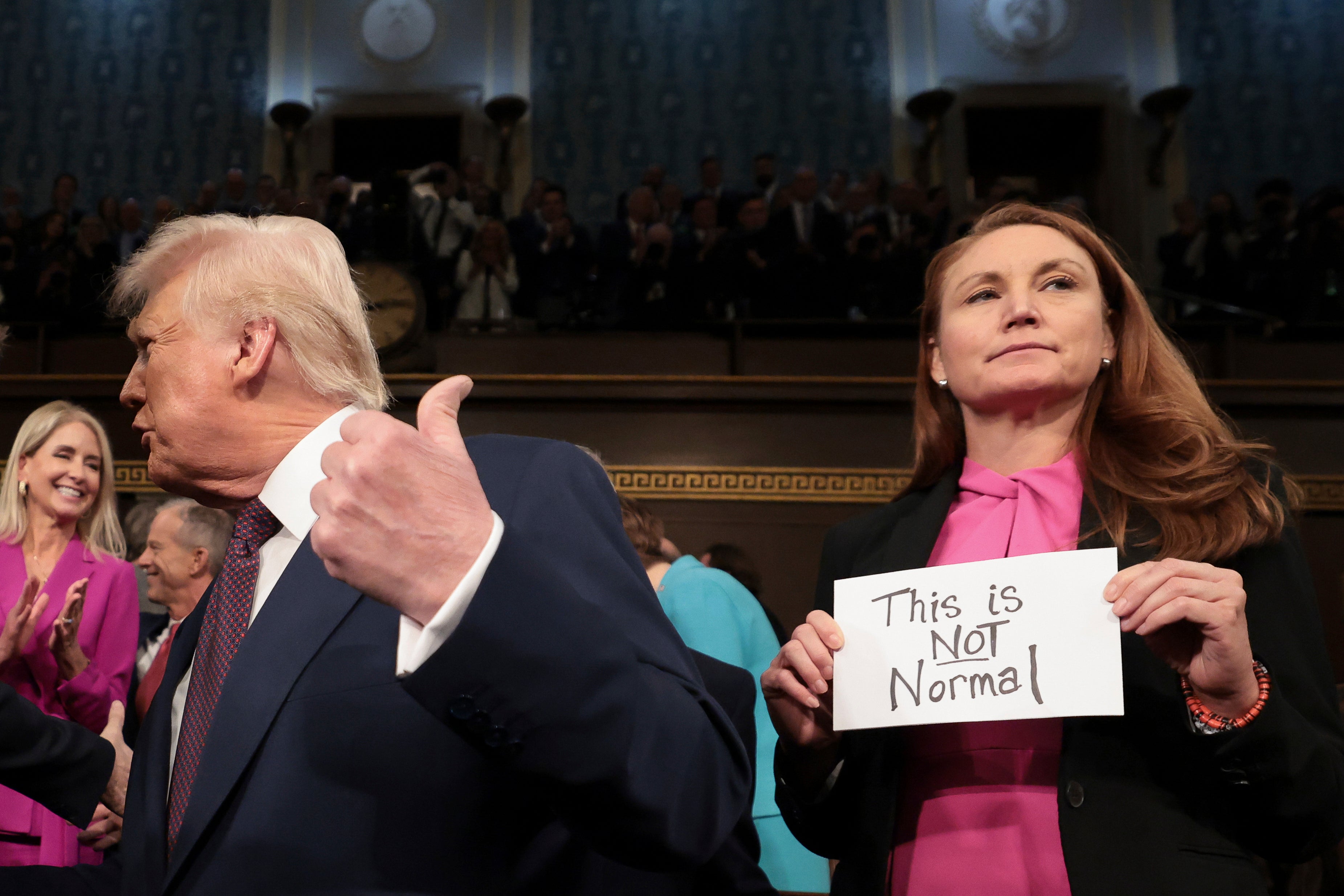 President Donald Trump arrives to address a joint session of Congress as Representative Melanie Stansbury, a Democrat from New Mexico, holds a sign at the Capitol on Tuesday reading: "This is not normal.”